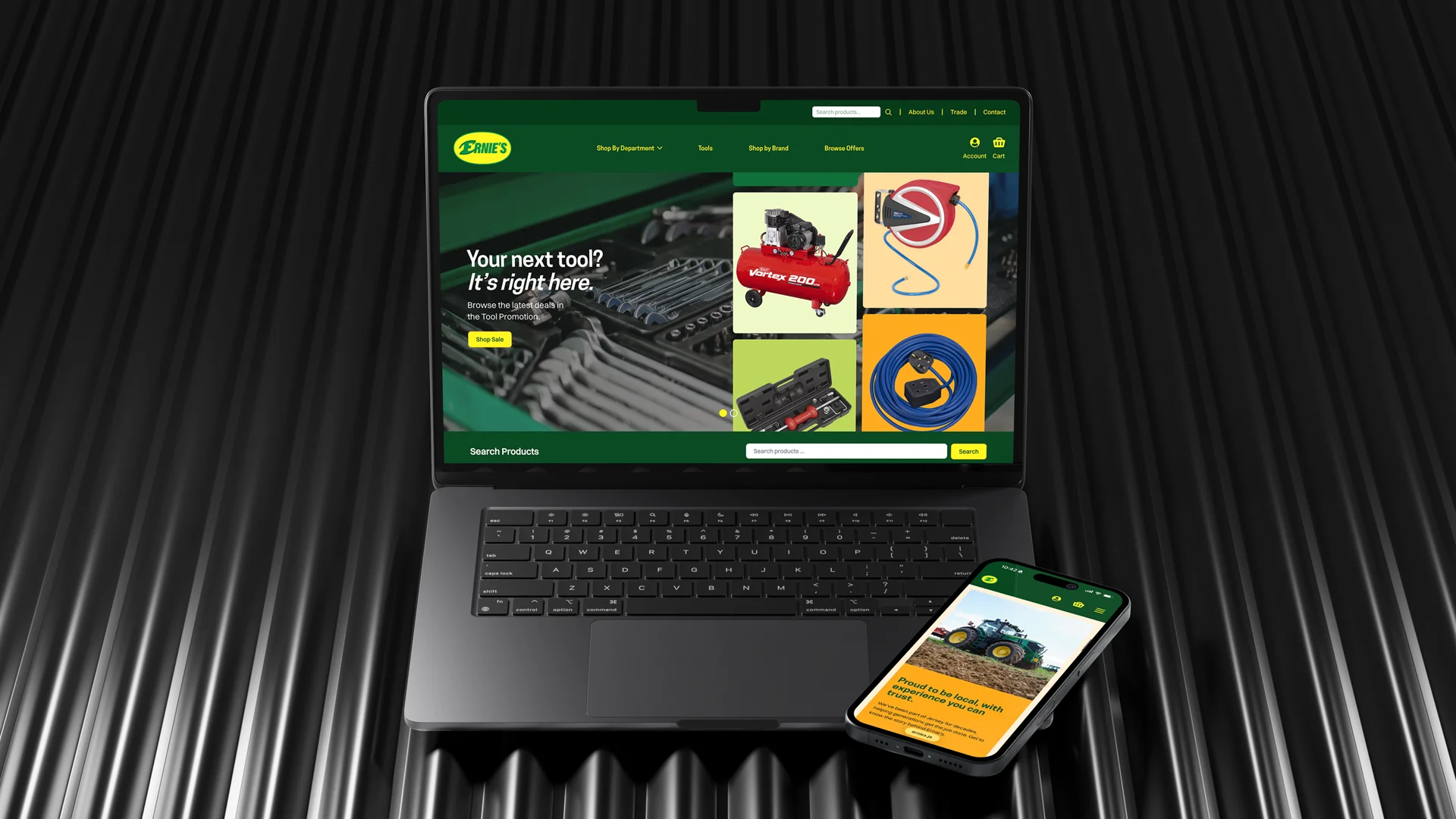 A laptop and smartphone displaying Ernie's tool store website with a green and yellow theme; the laptop shows tool images and a search bar, the phone shows a tractor and local expertise text.