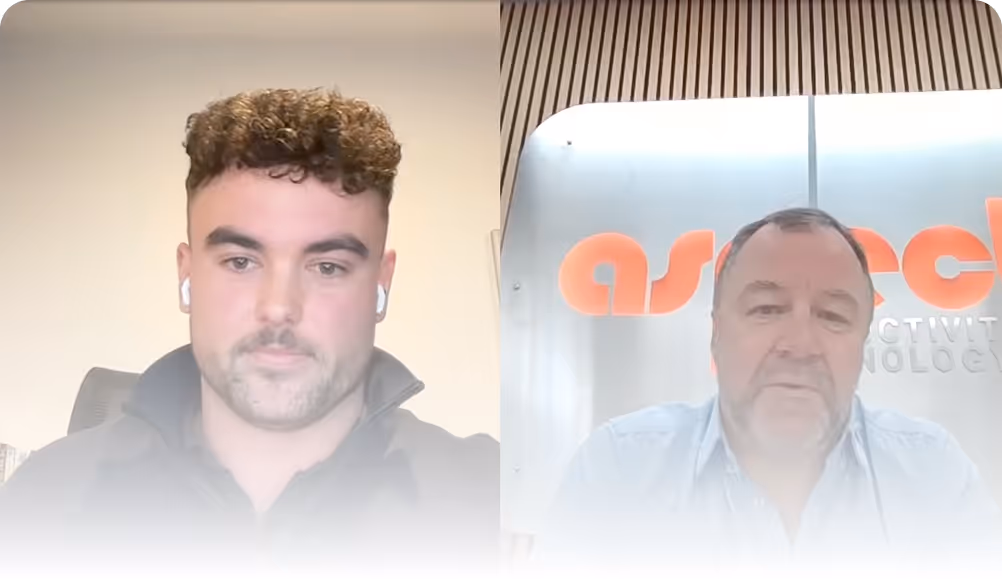 Two men in a video call, the left one with curly hair and earbuds, the right one in a light blue shirt in front of a sign with orange letters.