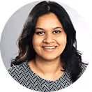 Smiling woman with shoulder-length black hair wearing a black and white patterned top.