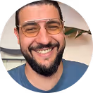 Smiling man with beard and glasses wearing a blue shirt.