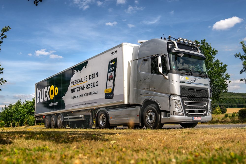 truckoo Sattelzug mit Werbebeklebung am Straßenrand, Seitenansicht