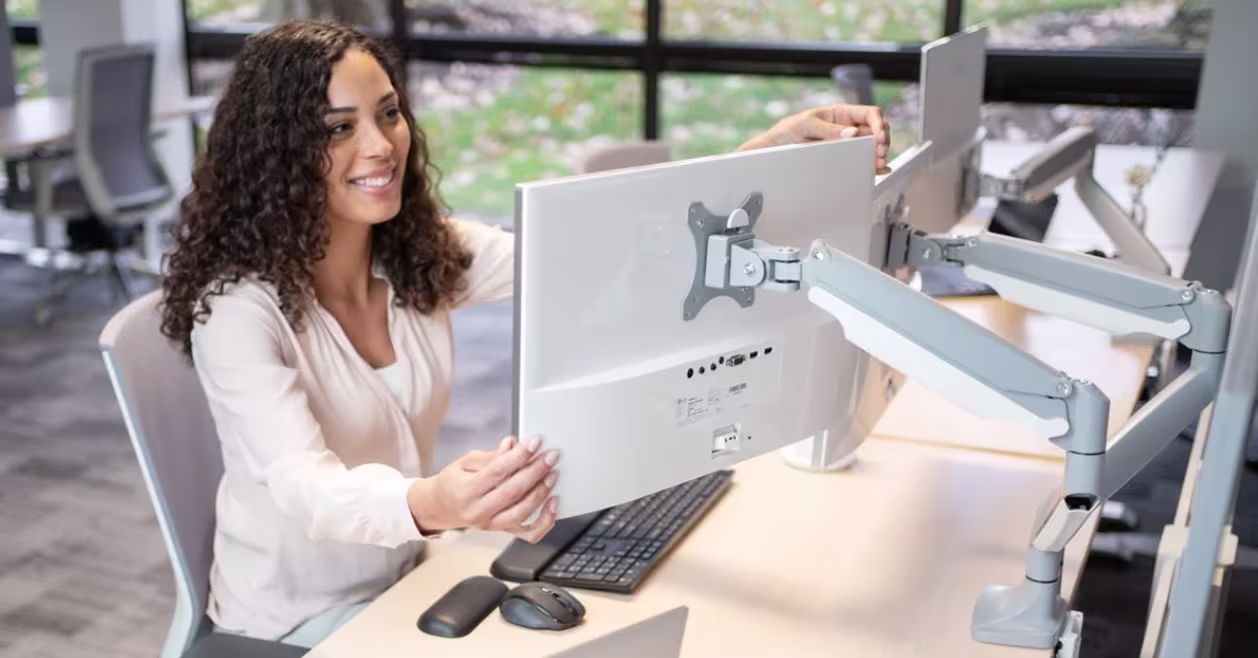 Woman at desk demonstrating proper monitor height and arm-length viewing distance.