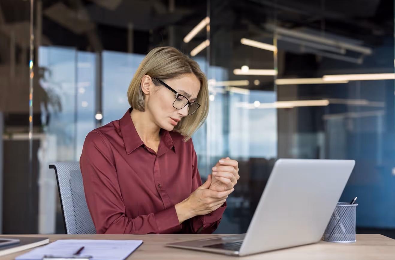 Office worker experiencing wrist pain from poor posture, highlighting need for the best ergonomic mouse