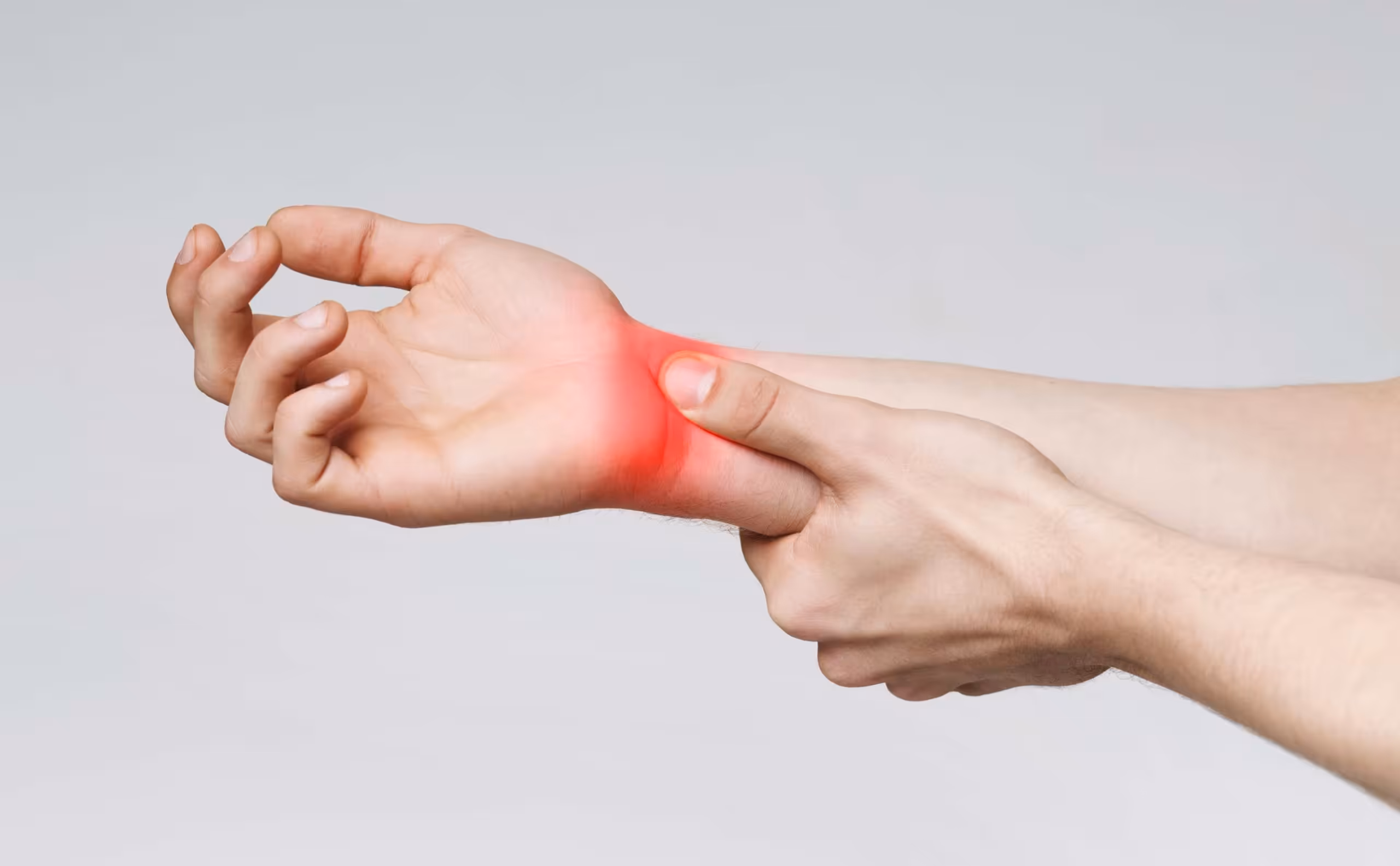 Close-up of a hand gripping the wrist, with a red highlighted area indicating pain and discomfort associated with carpal tunnel syndrome.