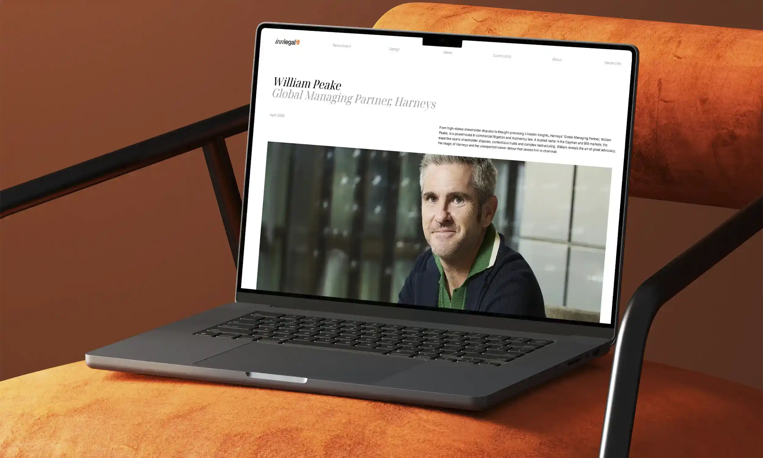Laptop on an orange chair displaying an article with a photo of a William Peake, Global Managing Partner, Harneys.