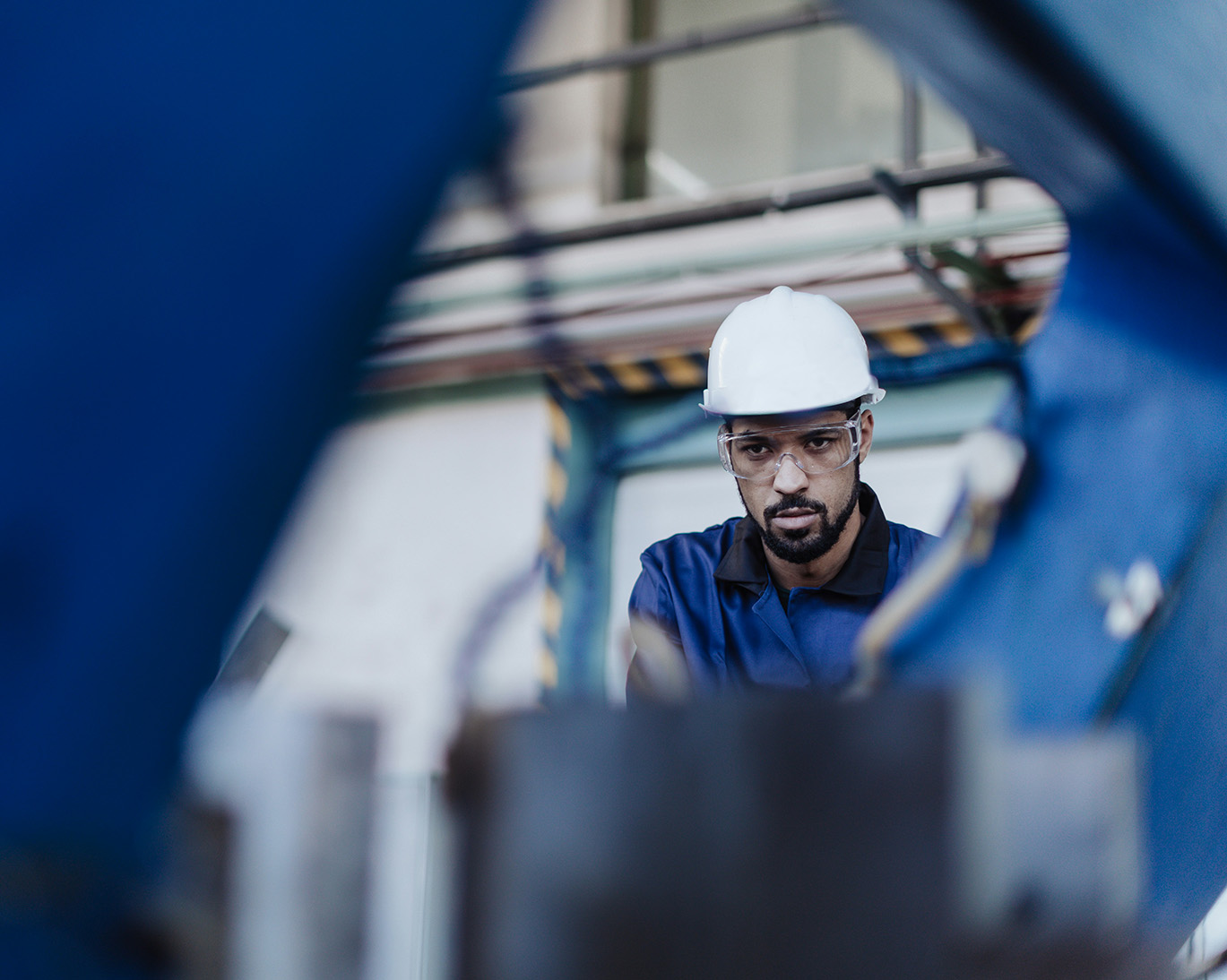 A man in a hard hat surrounded by manufacturing equipment.