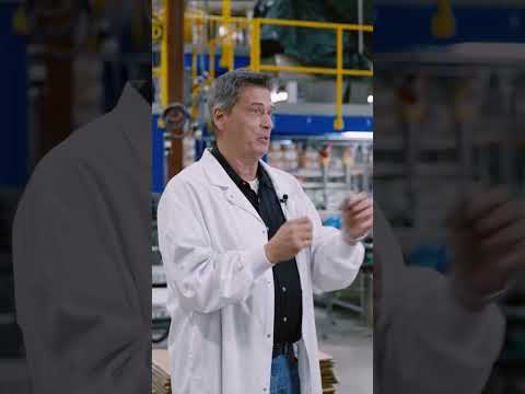 Carl Tokarek of Maneva, in a white lab coat, explains VITA on a factory floor.