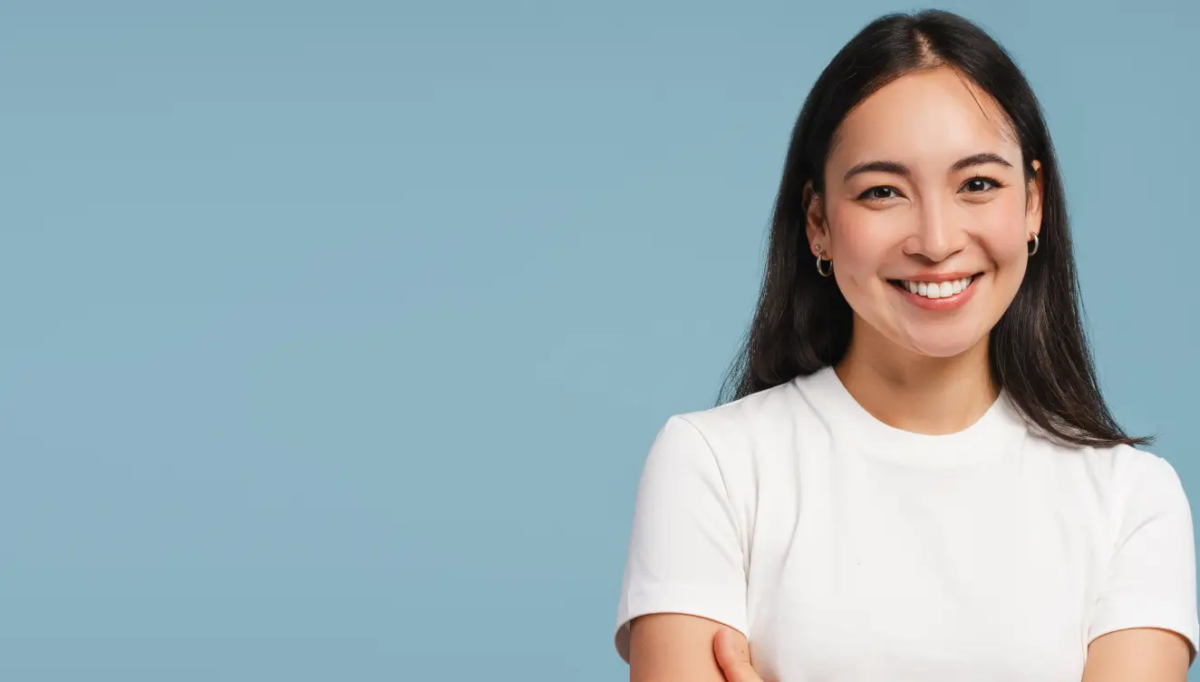 A person in a white shirt smiles, standing against a solid blue background.