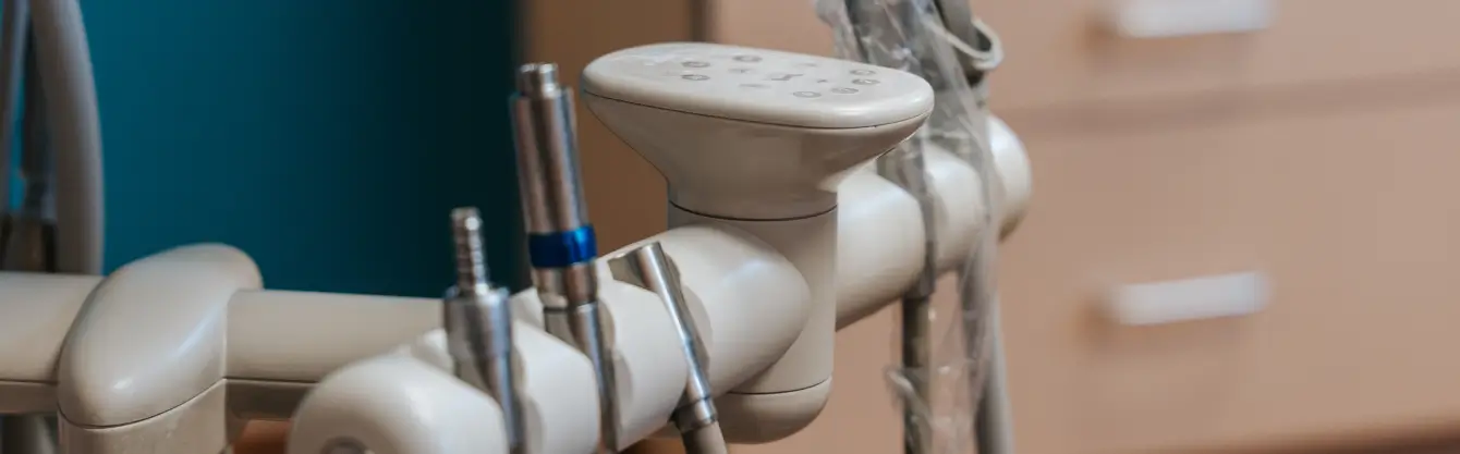 Close-up of dental equipment with various dental tools attached, positioned in a dental office.