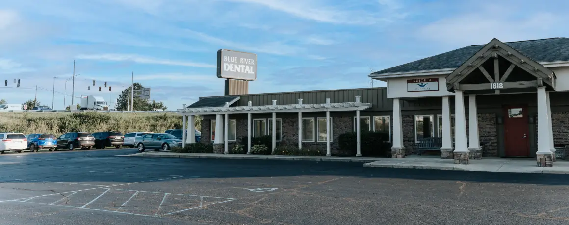 A dental clinic with a sign reading "Blue River Dental" and an empty parking lot in front.