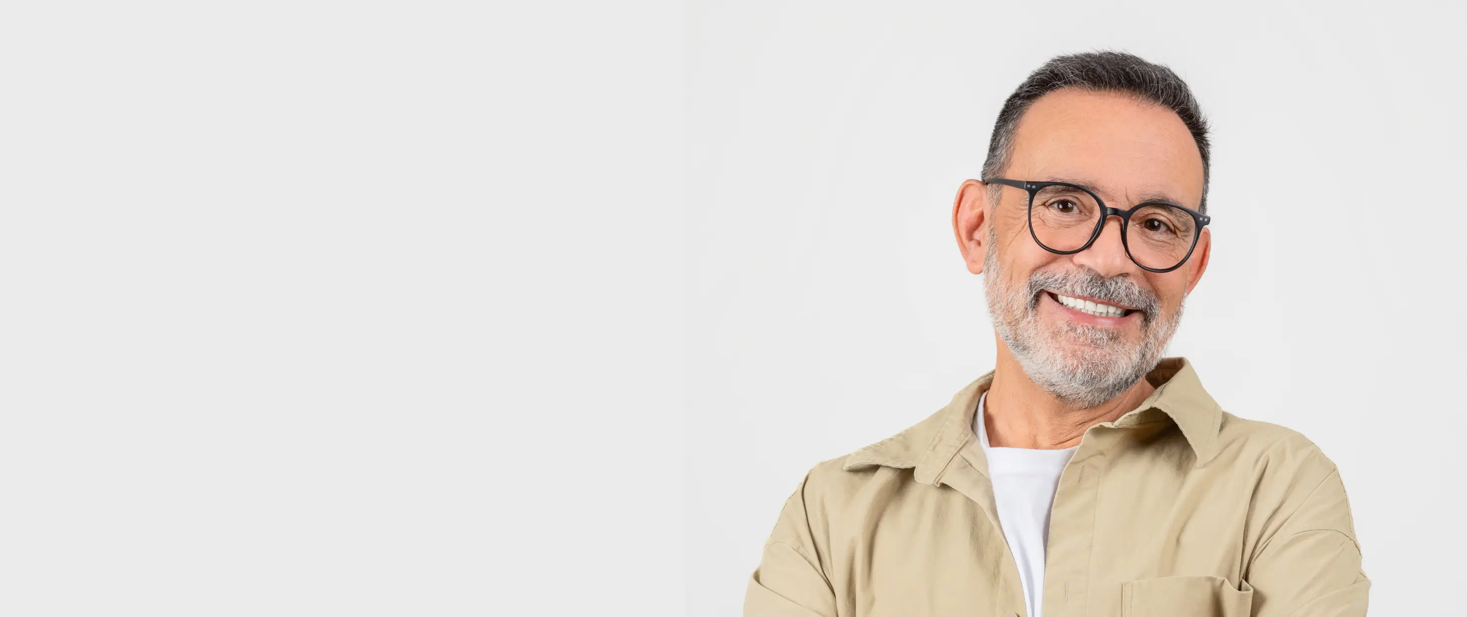 A smiling man with glasses and a beard stands against a plain white background.