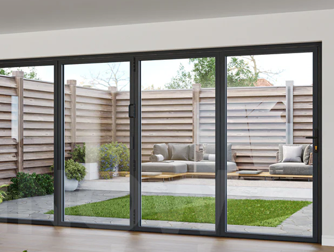 Modern black-framed bi-fold glass doors opening to a patio with outdoor seating and green lawn enclosed by a wooden fence.