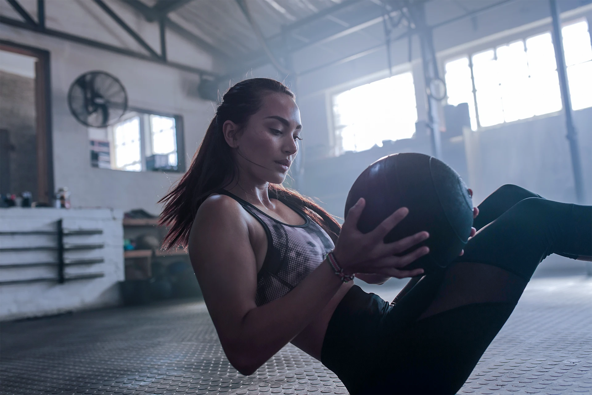 Gym goer performs Russian twists using a medicine ball.