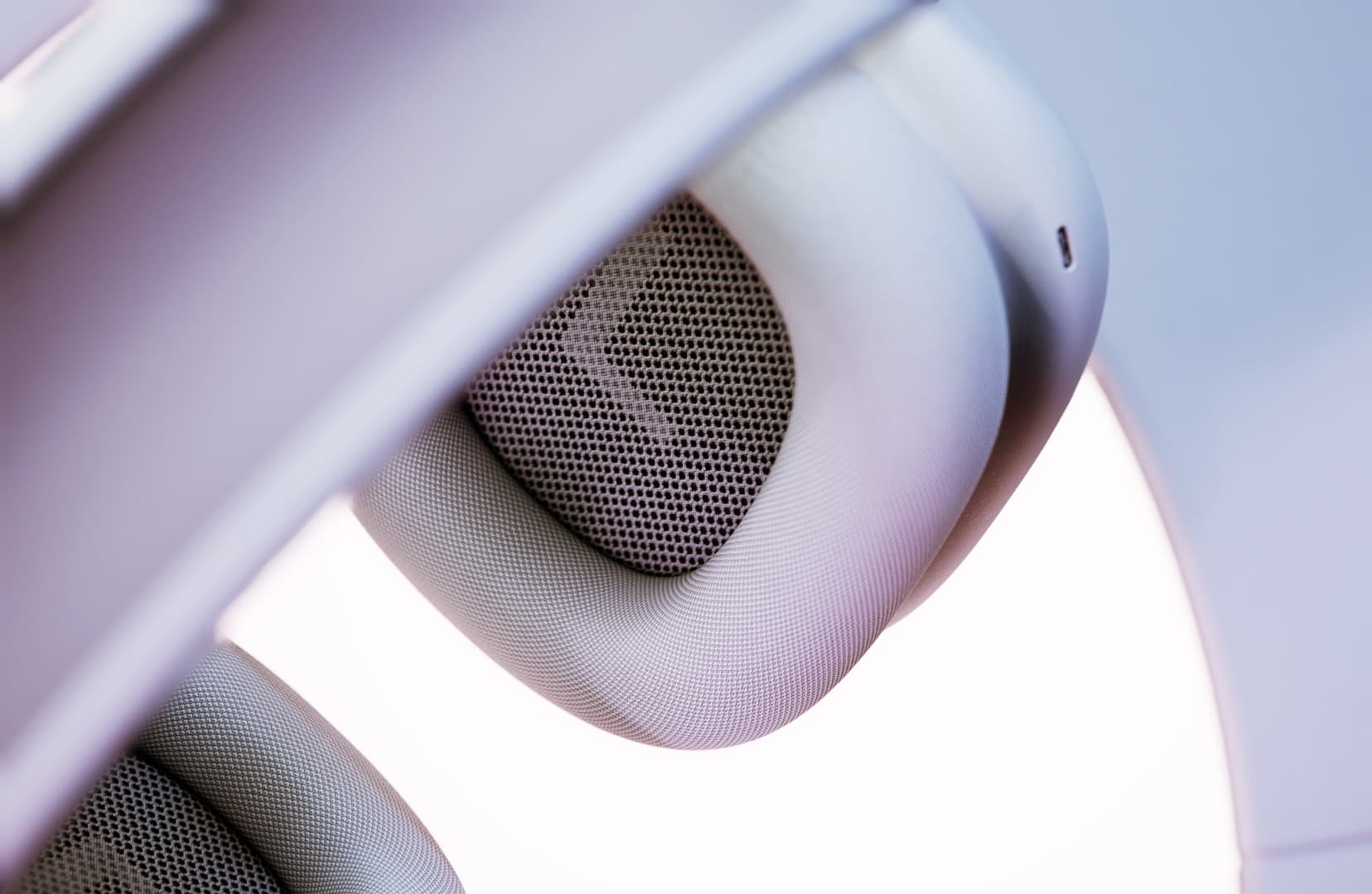 Primer plano de la almohadilla y rejilla interior de unos auriculares blancos.
