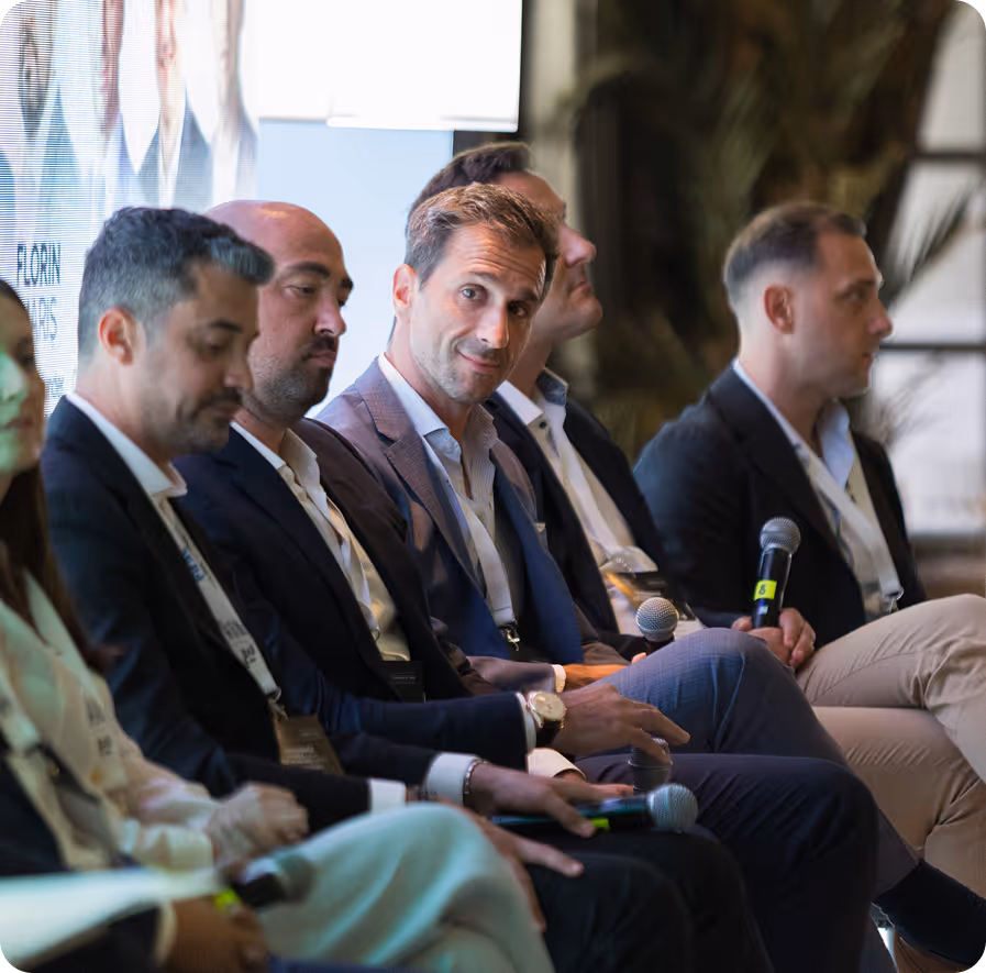 Group of business professionals seated and engaged in a panel discussion or meeting.