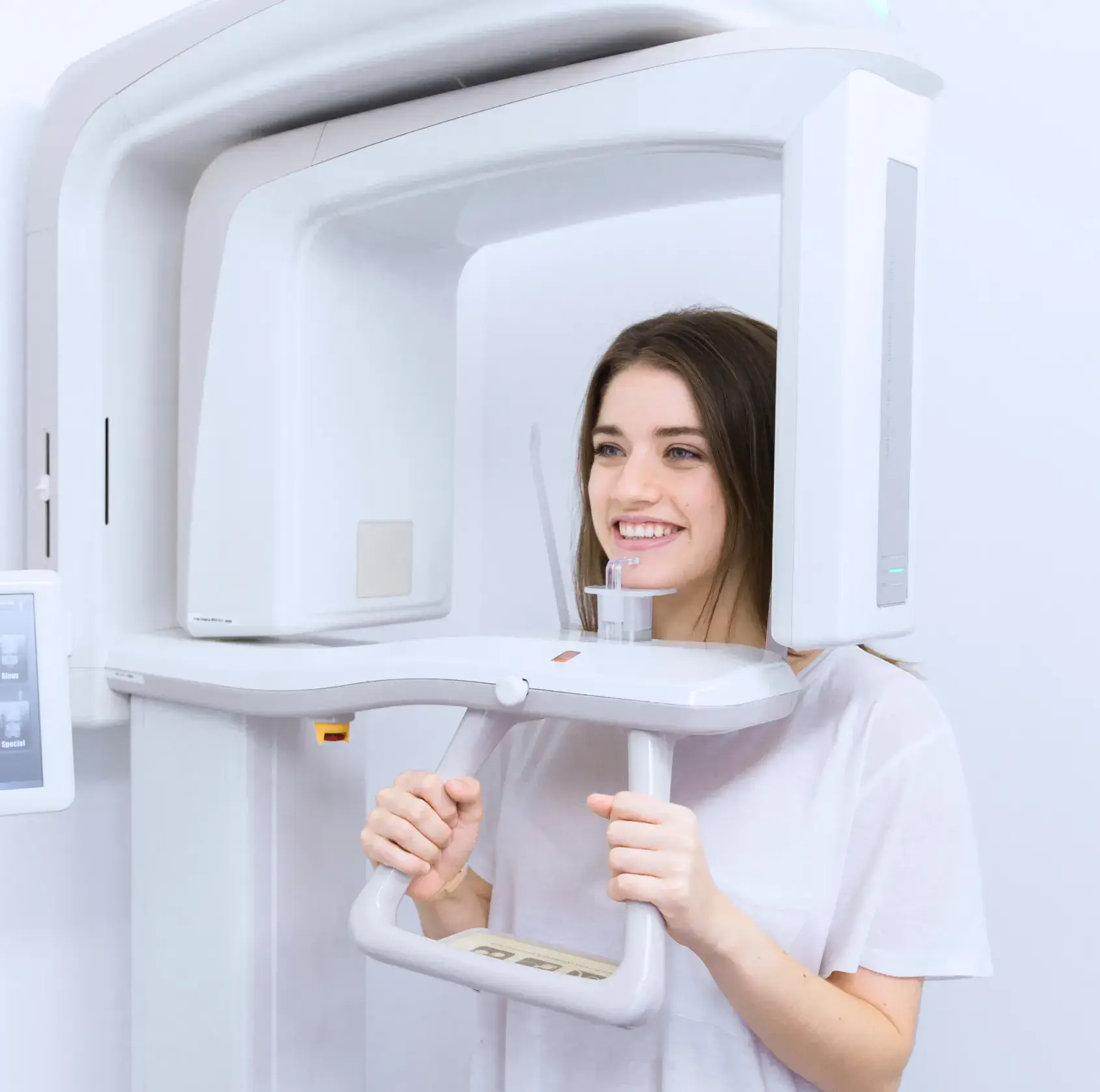 Young woman undergoing a dental X-ray scan using a panoramic dental imaging machine.