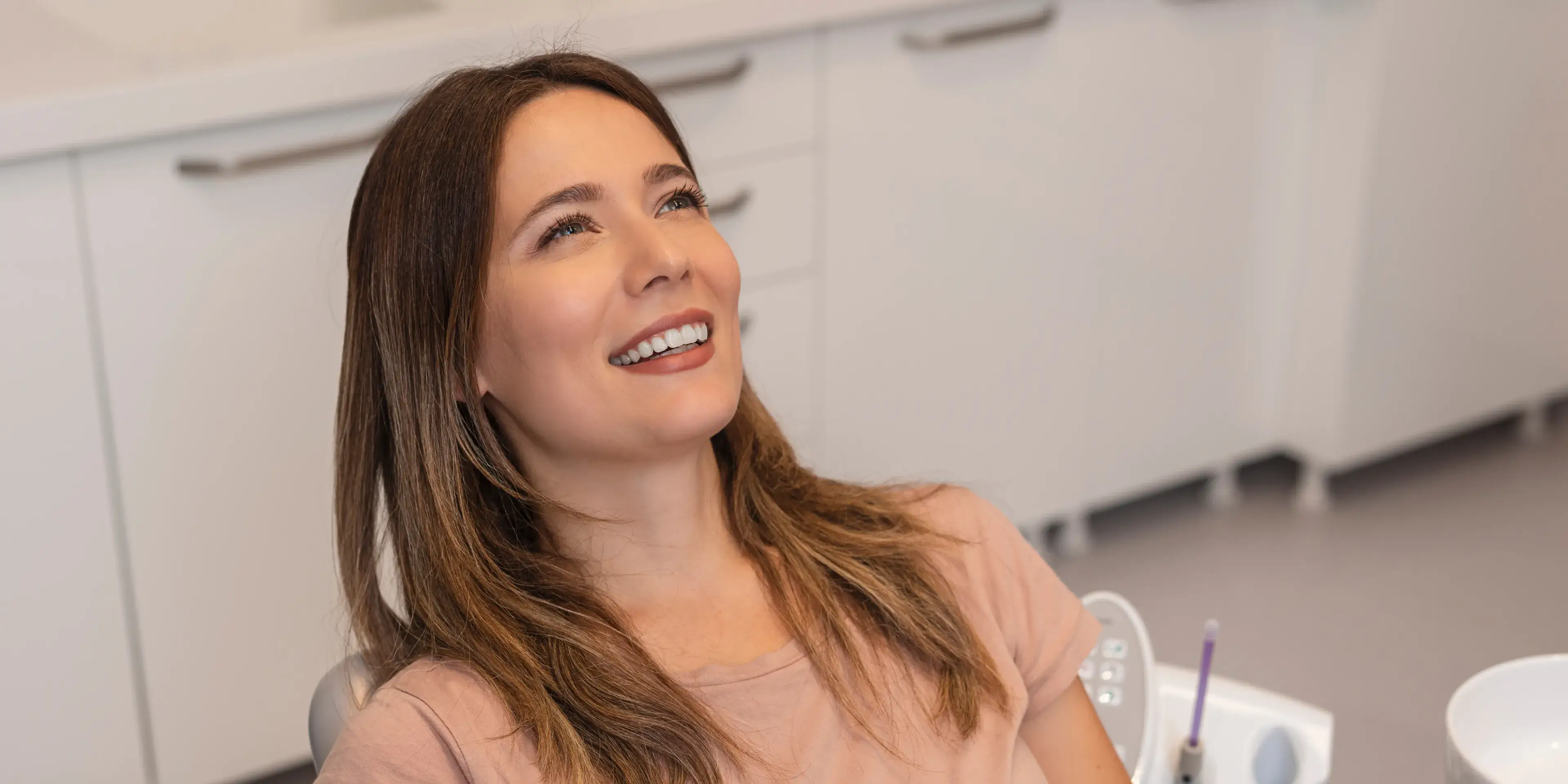 Smiling woman reclining in a dental chair in a clinic setting.
