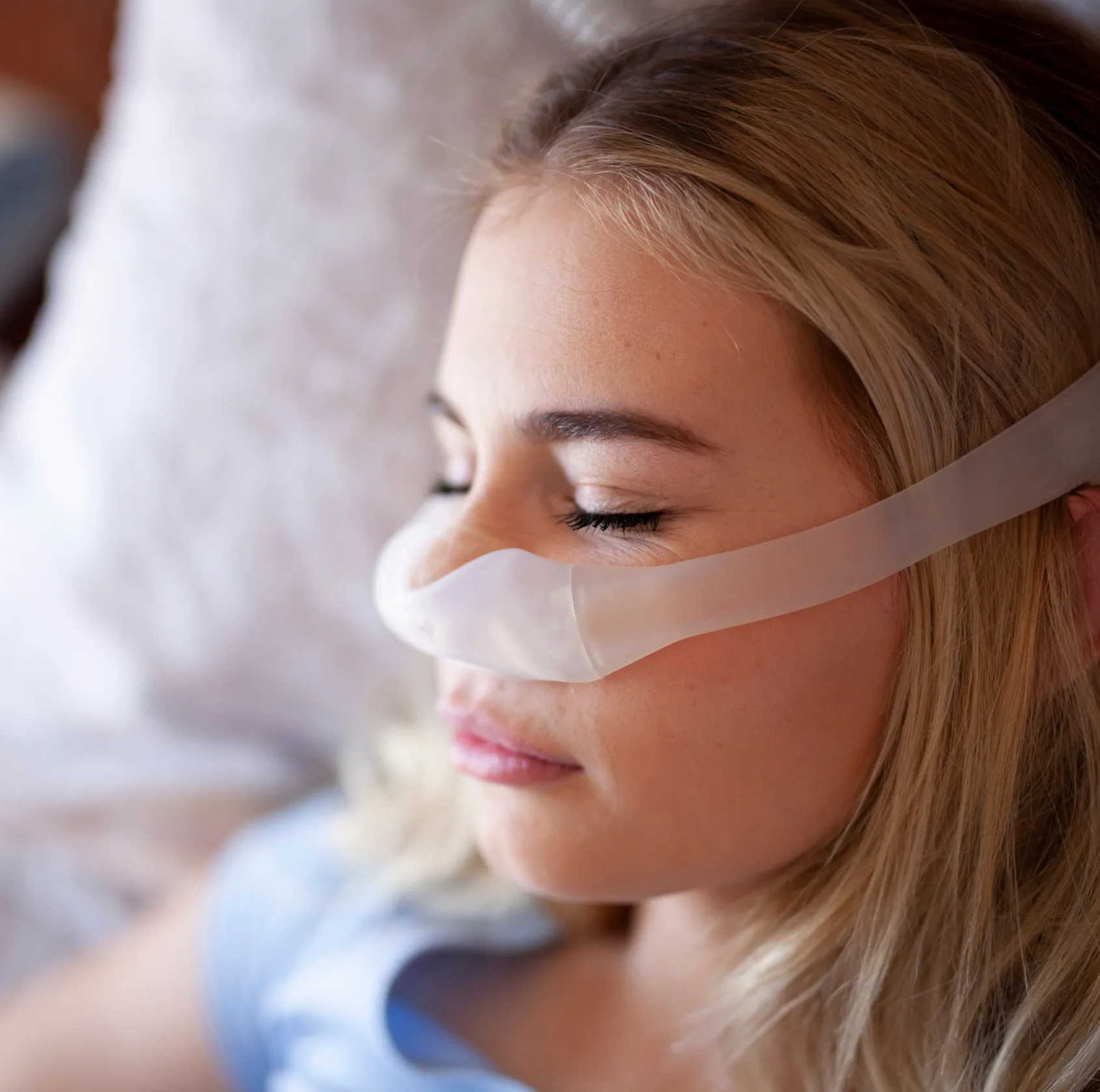 Close-up of a woman resting with eyes closed wearing a nasal oxygen tube.
