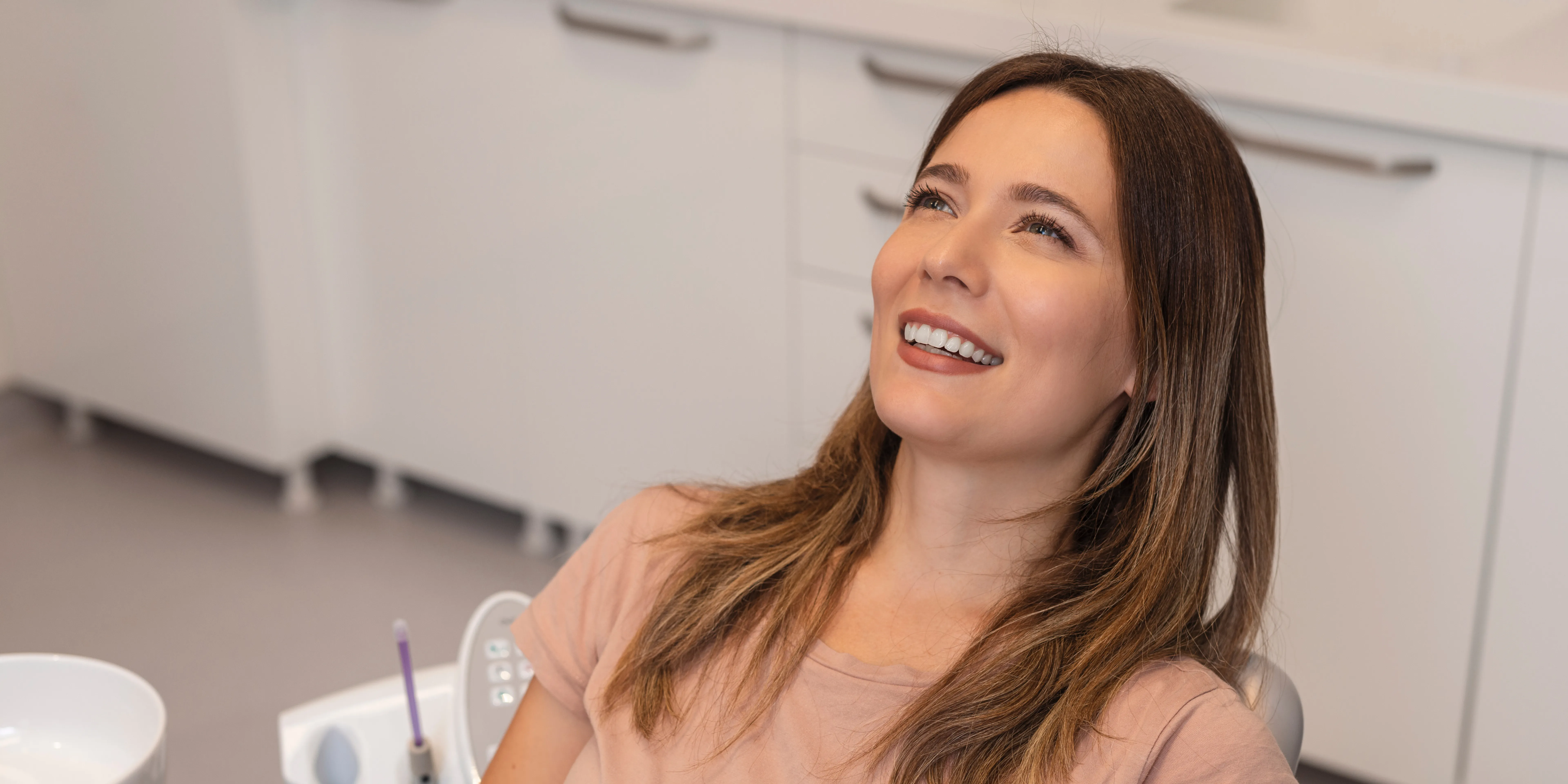 Smiling woman reclining in a dental chair in a modern dental office.