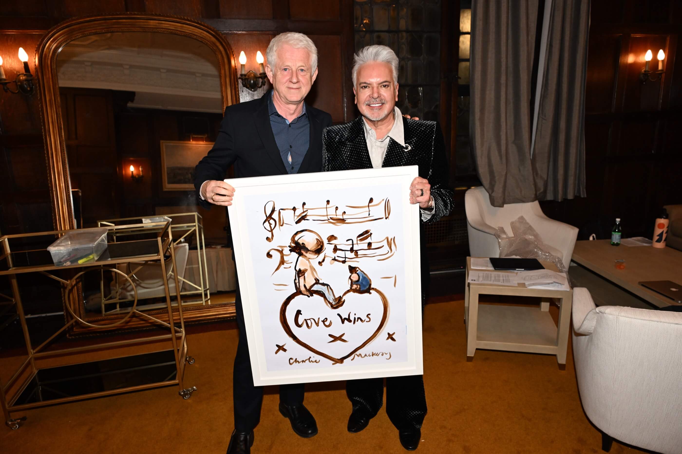 Woman in a red dress with braided hair sings into a microphone on a stage with blue curtains.