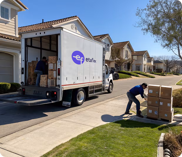 Delivery truck with Etaflex logo parked on a suburban street while two workers handle cardboard boxes on the sidewalk and inside the truck.