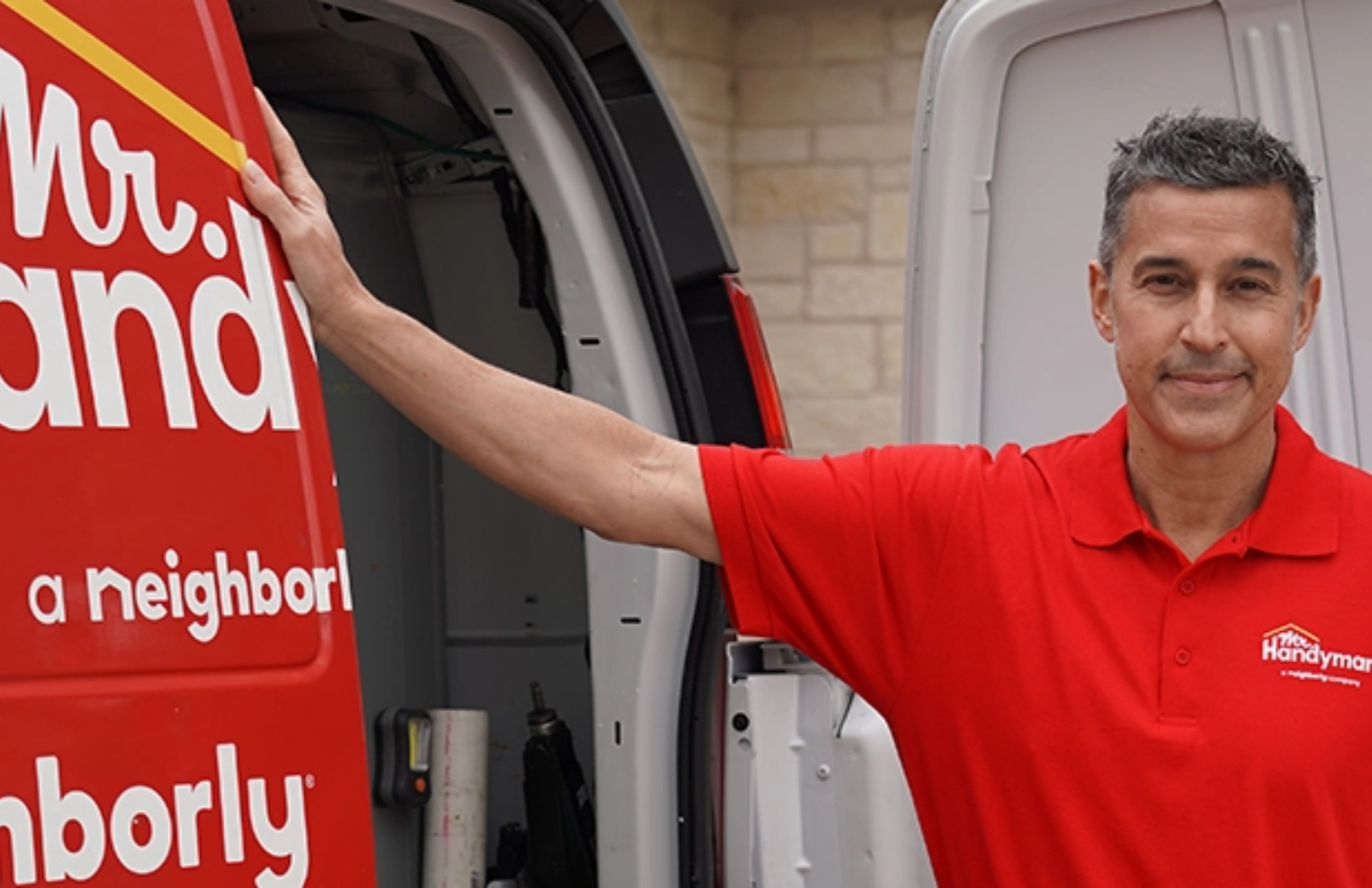 Mr. Handyman service professional standing by red service van