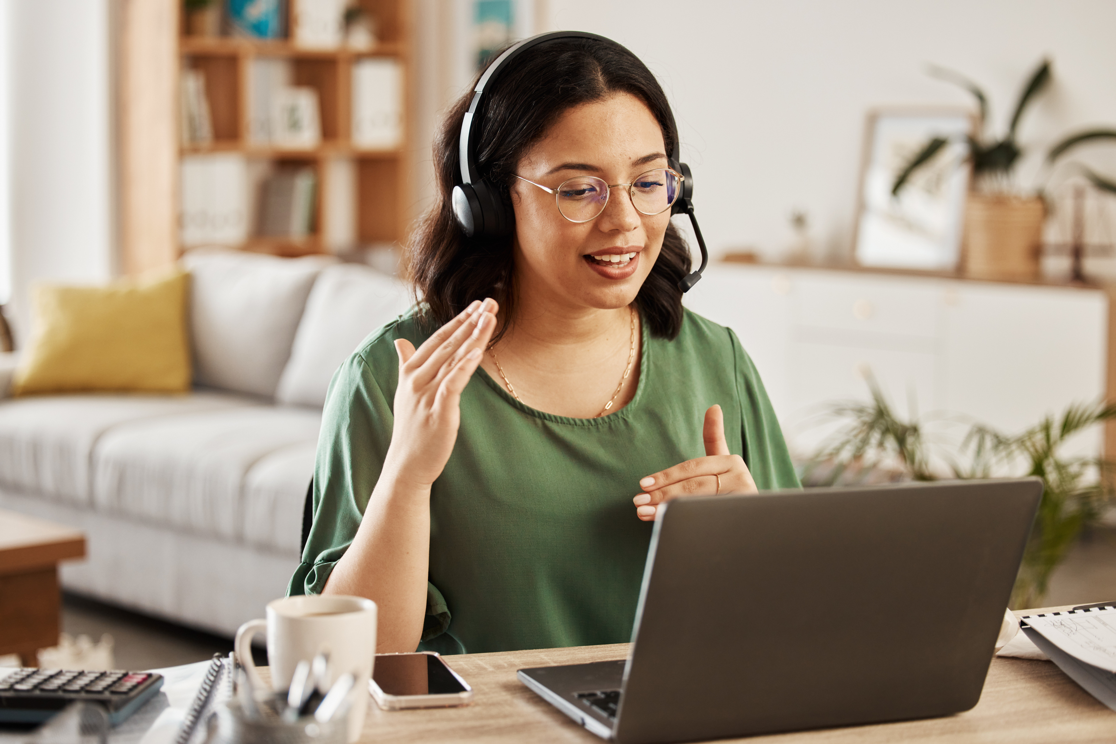 Woman with headset gesturing during video call at home office