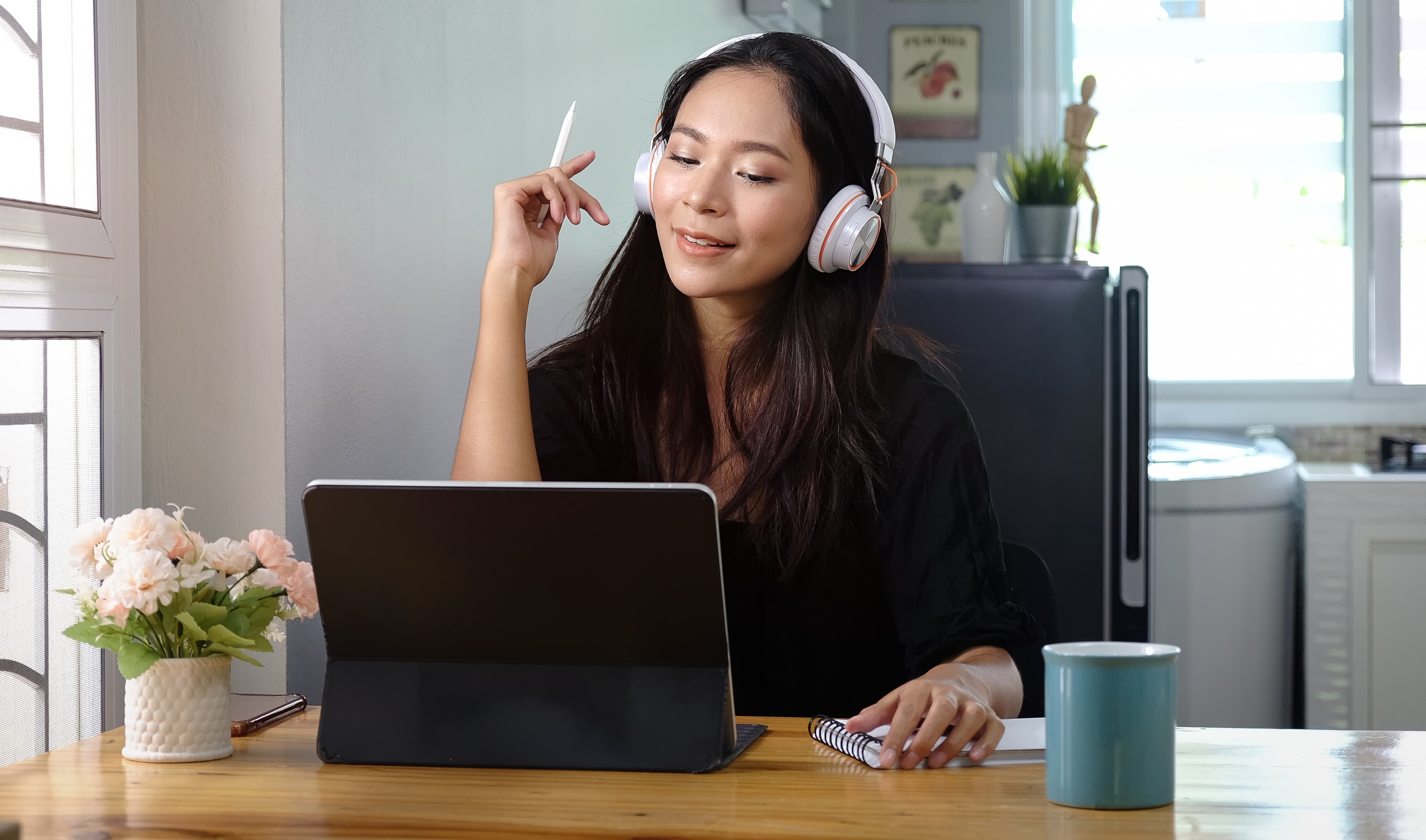 Woman wearing headphones enjoying music while working on laptop at home