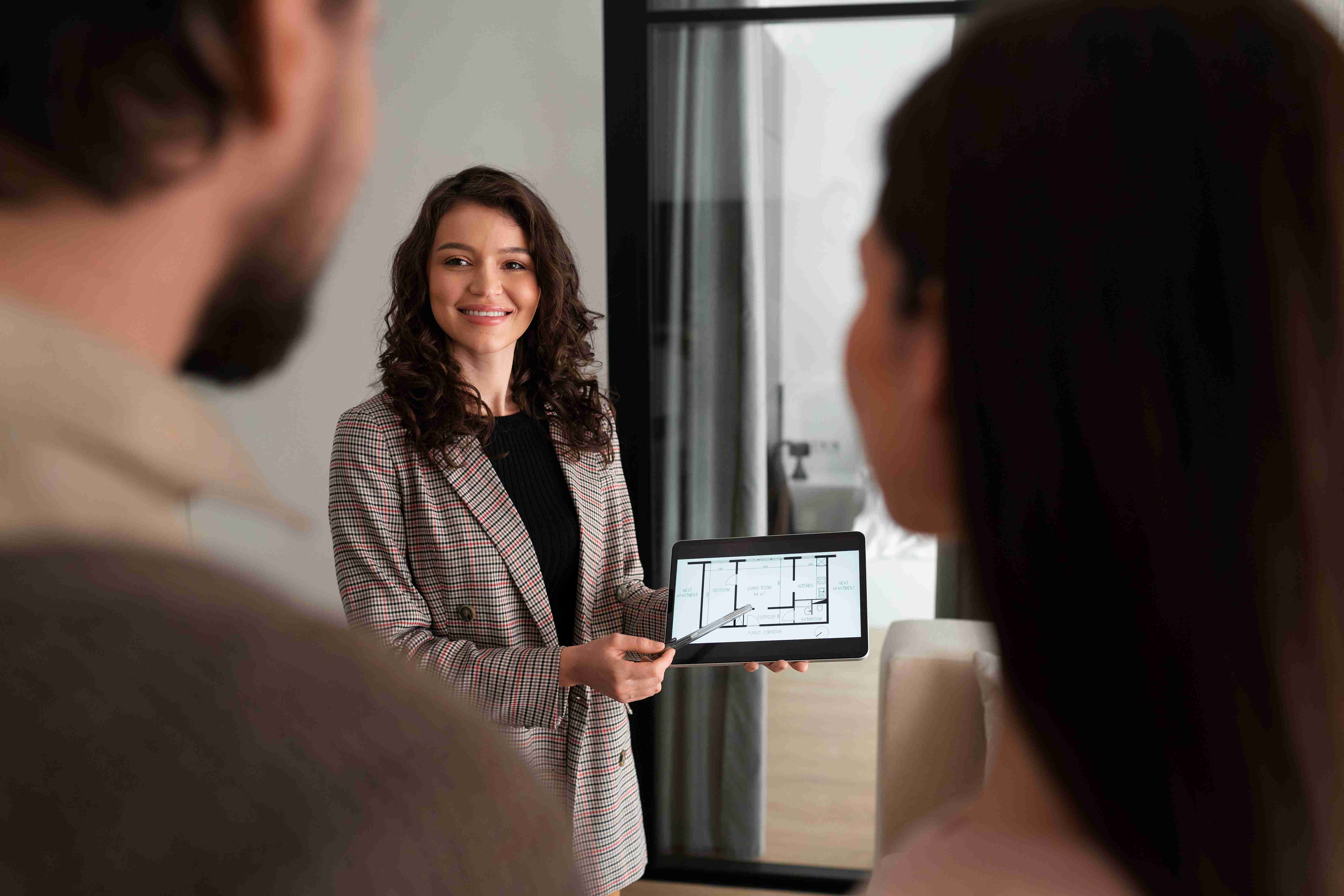 Woman presenting floor plan on tablet during business meeting