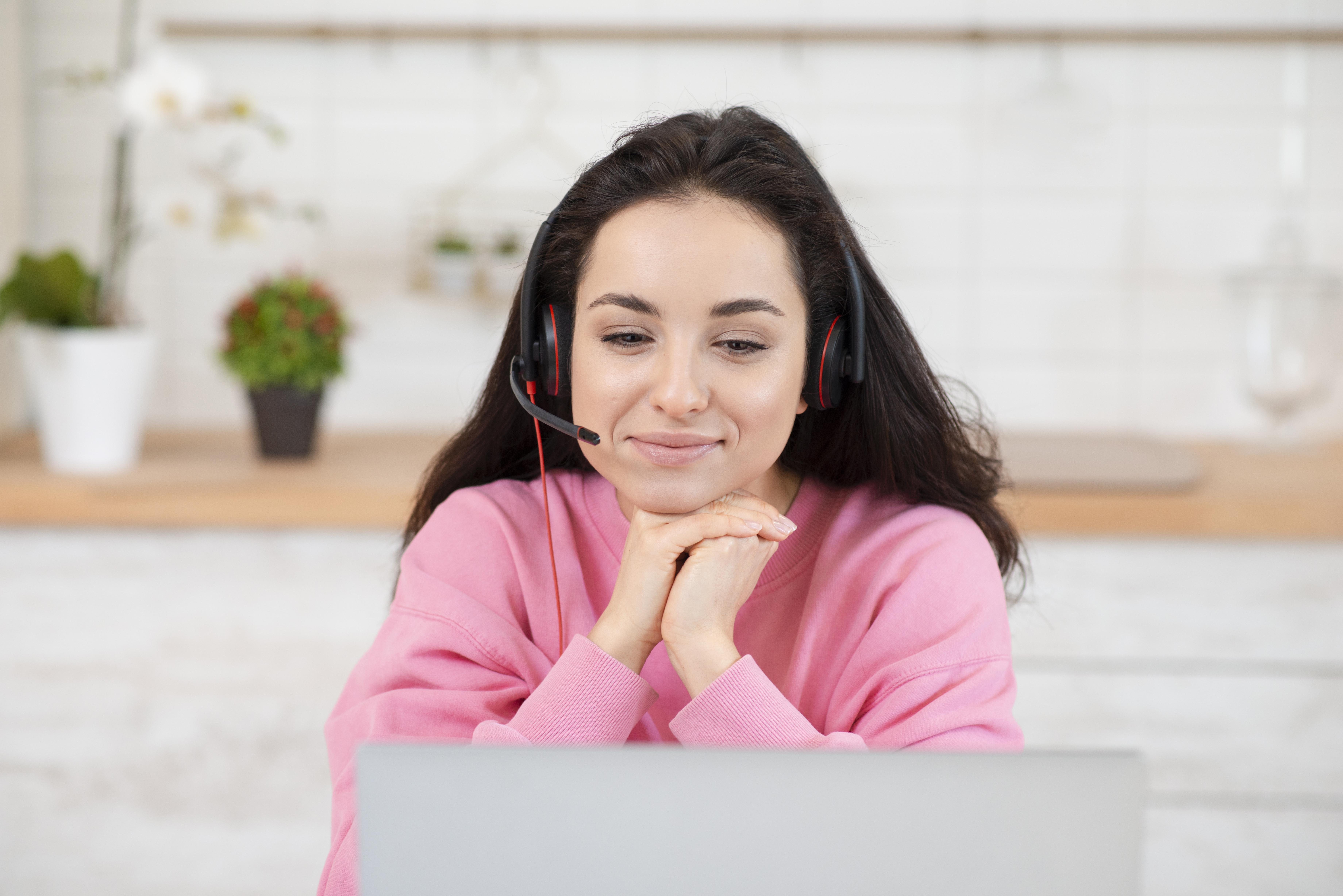 Customer service representative wearing headset smiling at laptop