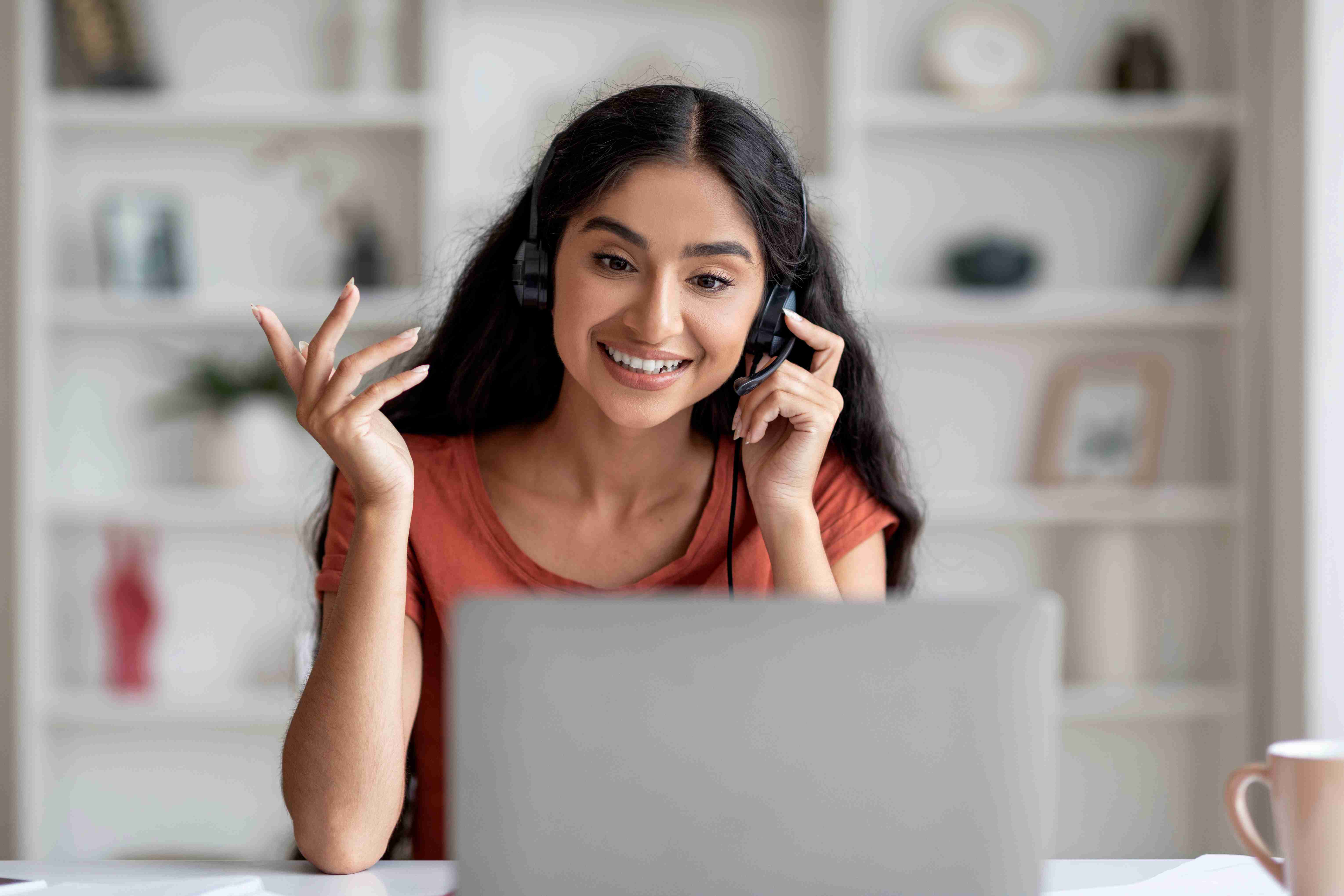 Smiling customer service representative wearing headset working at laptop