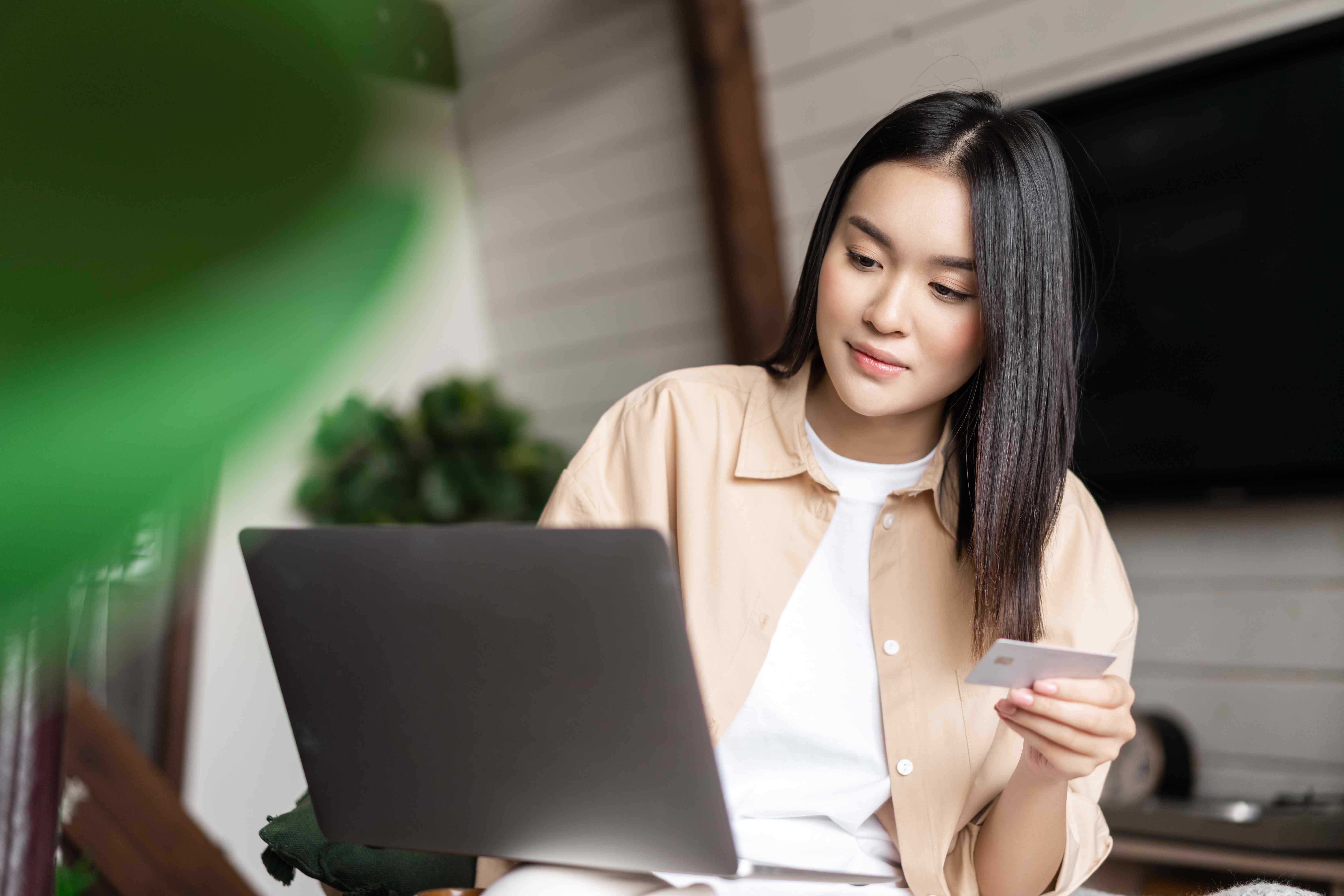Woman working on laptop and holding credit card at home office