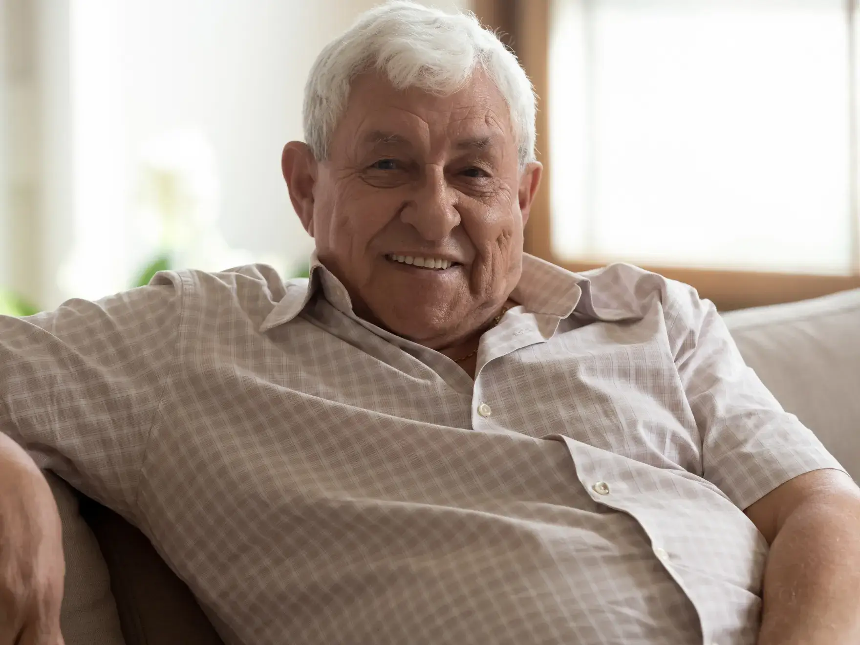an older man sitting on a couch smiling