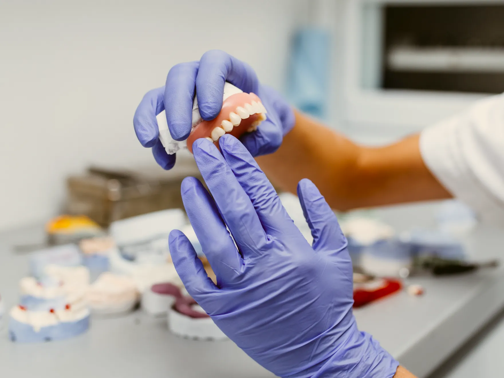 a person in a white shirt and purple gloves is putting a toothpaste on