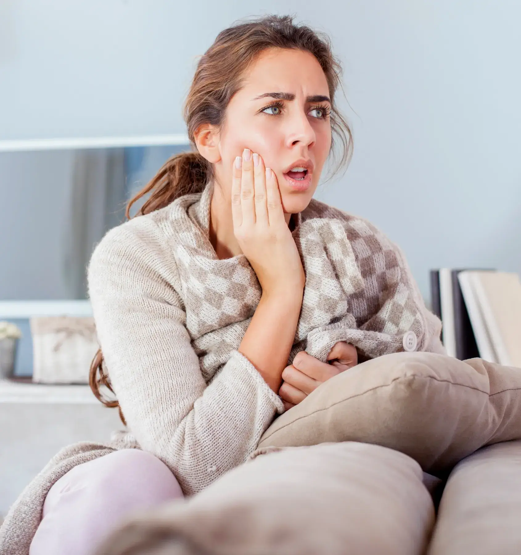 a woman sitting on a couch with her hand on her face