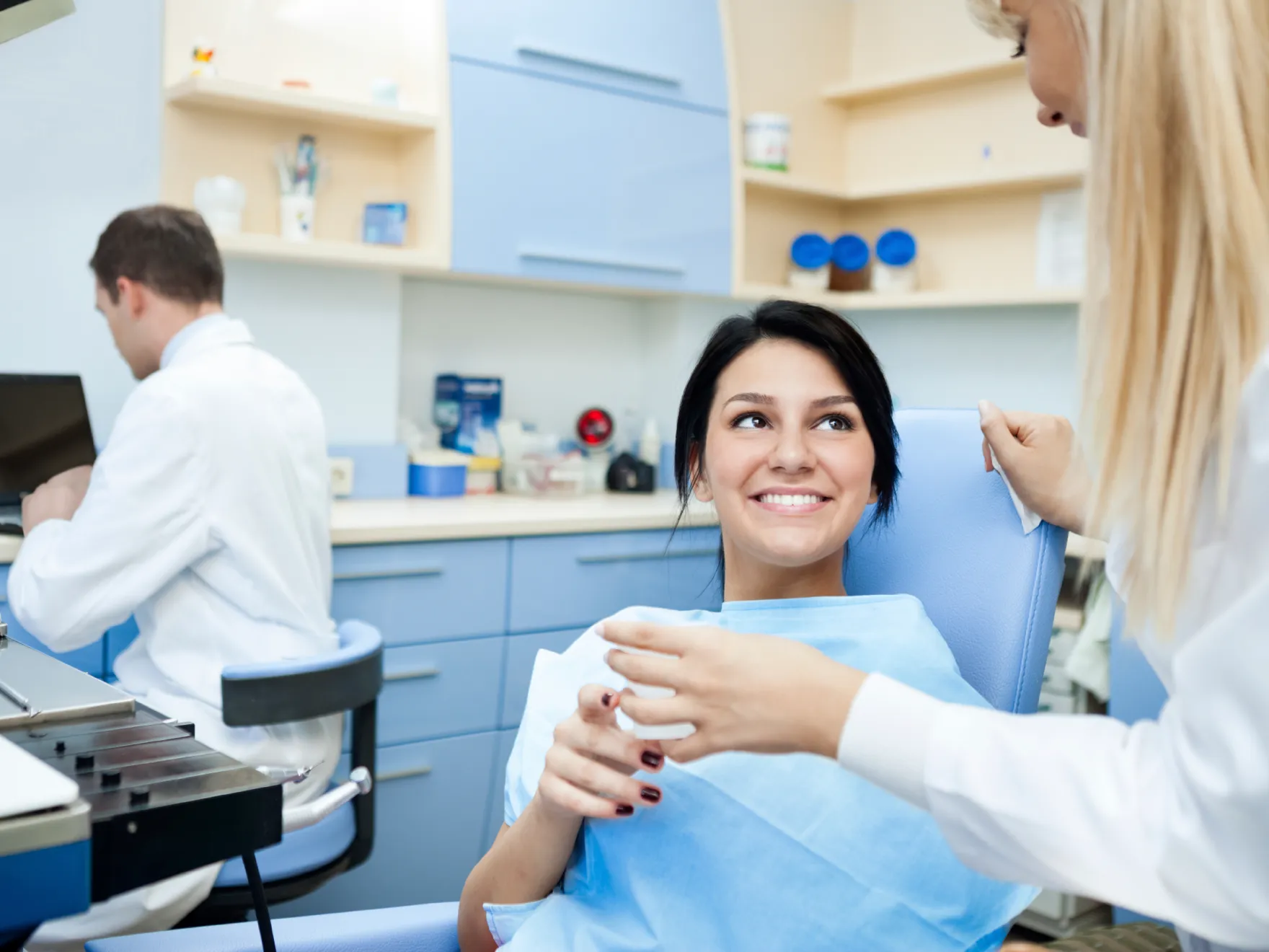 a woman getting her teeth brushed by a dentist