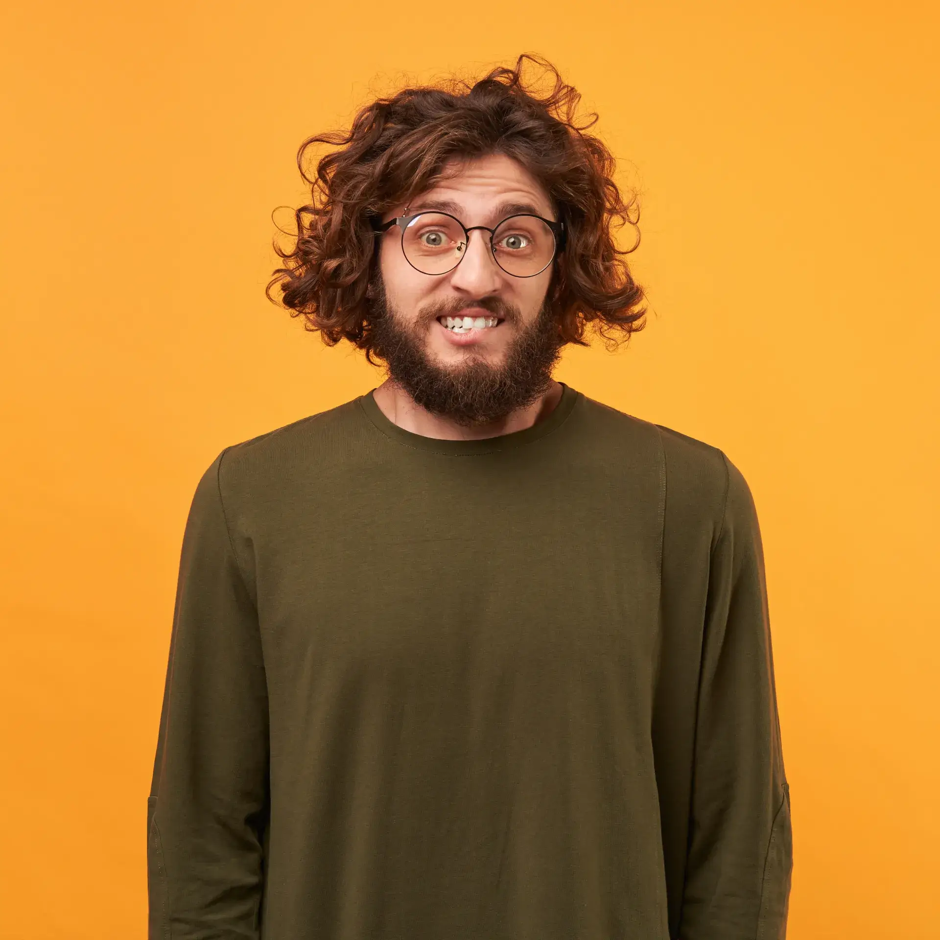 a man with a beard and glasses standing in front of a yellow background