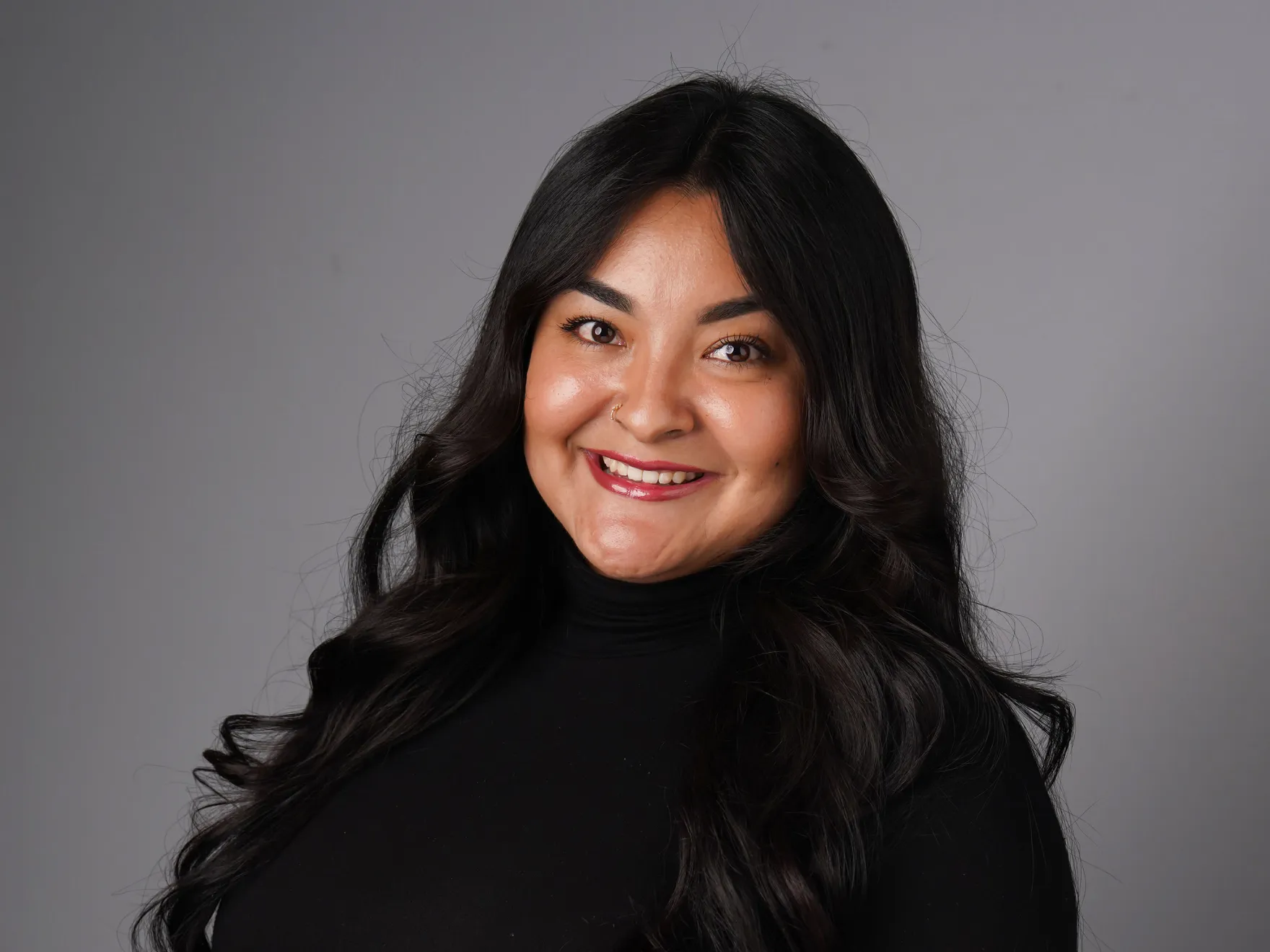 a woman with long black hair and a black turtle neck top