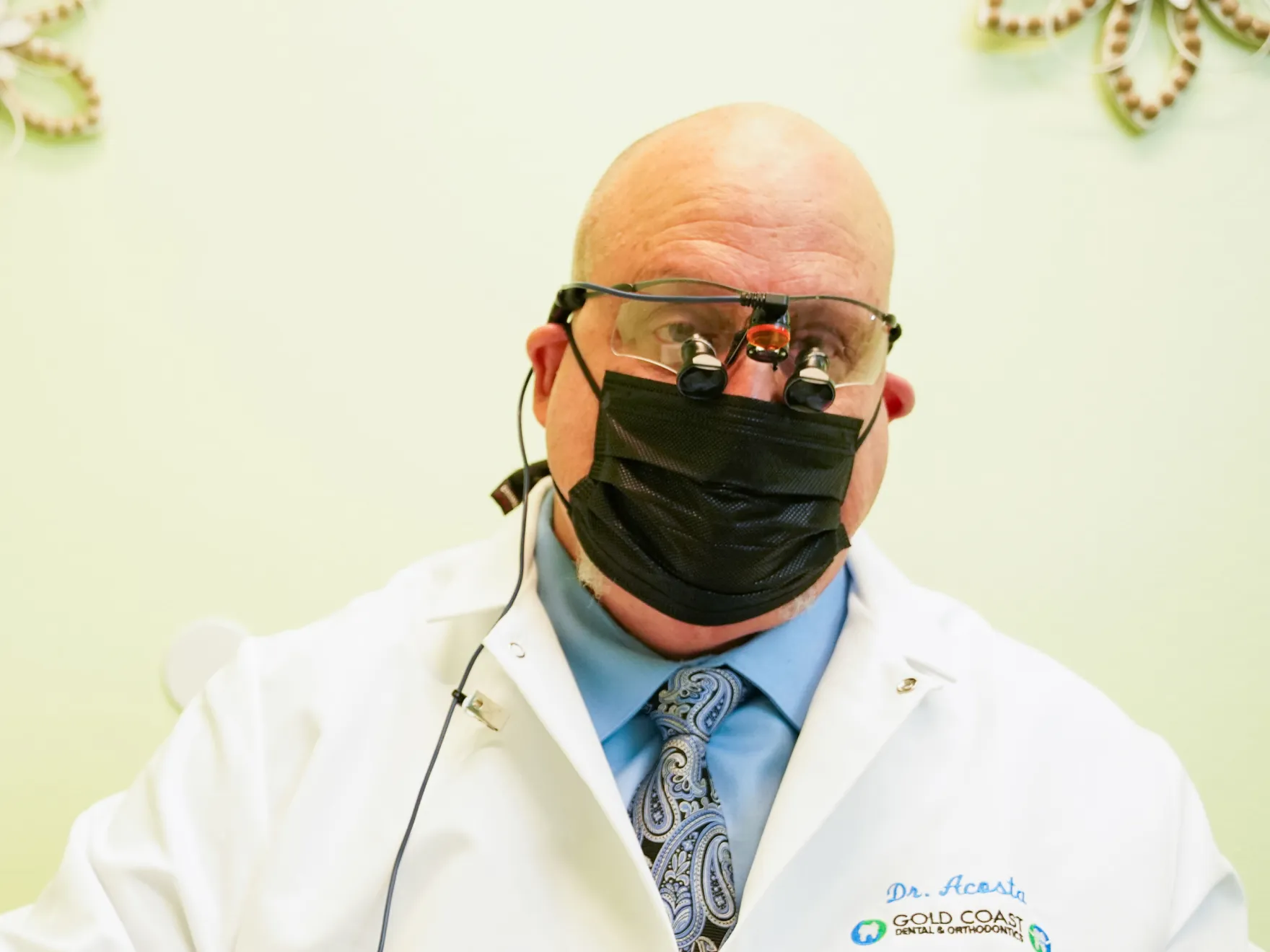 a man in a lab coat and tie wearing a mask