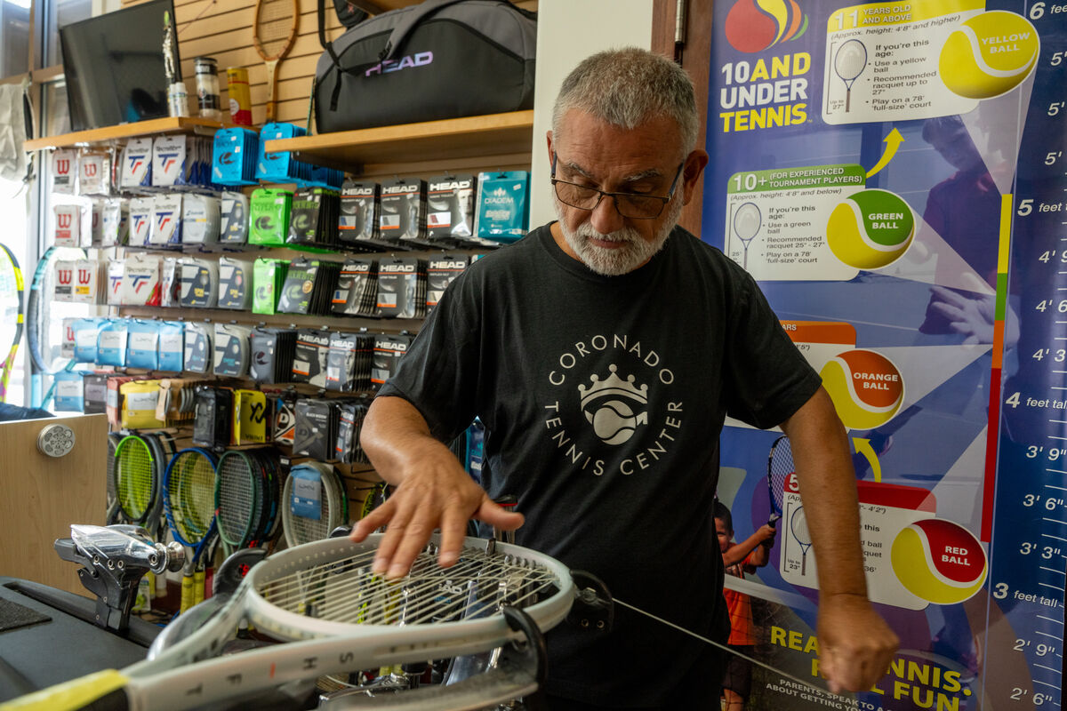 A man performing maintenance on a tennis racket.