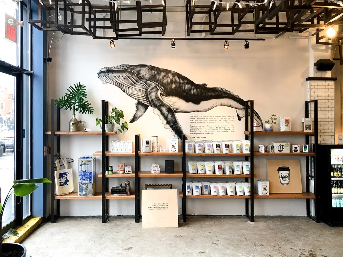 Whale mural printed on a coffee shop wall above shelves of coffee products.