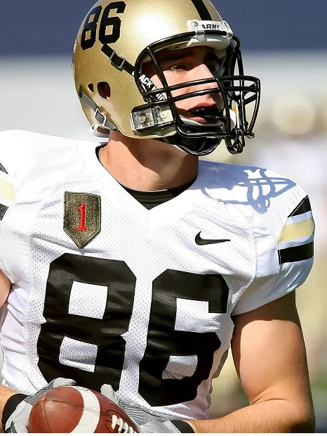 American football player wearing a gold helmet with number 86 and white jersey holding a football.