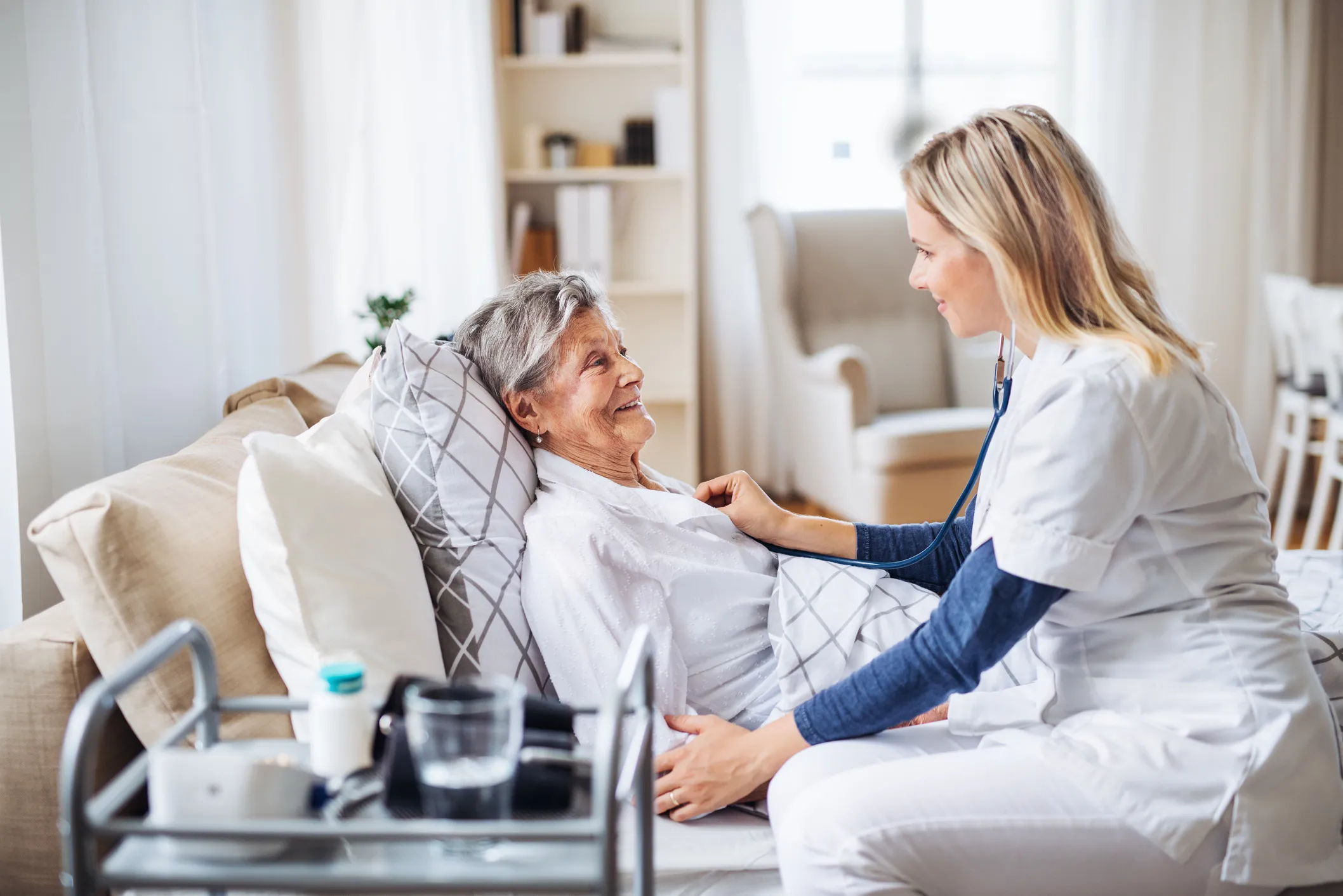 Caregiver checking in on an older woman resting at home