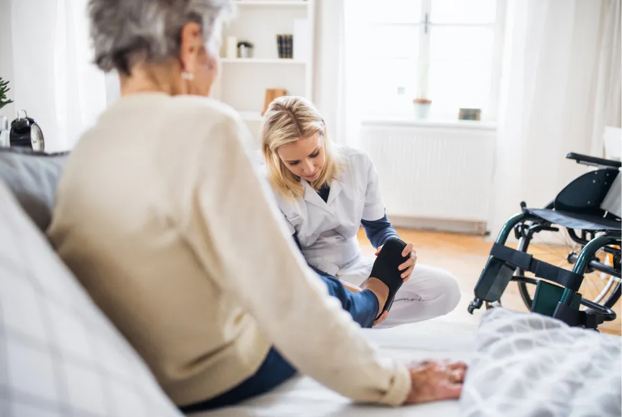 In Home Care worker putting on elder women shoes