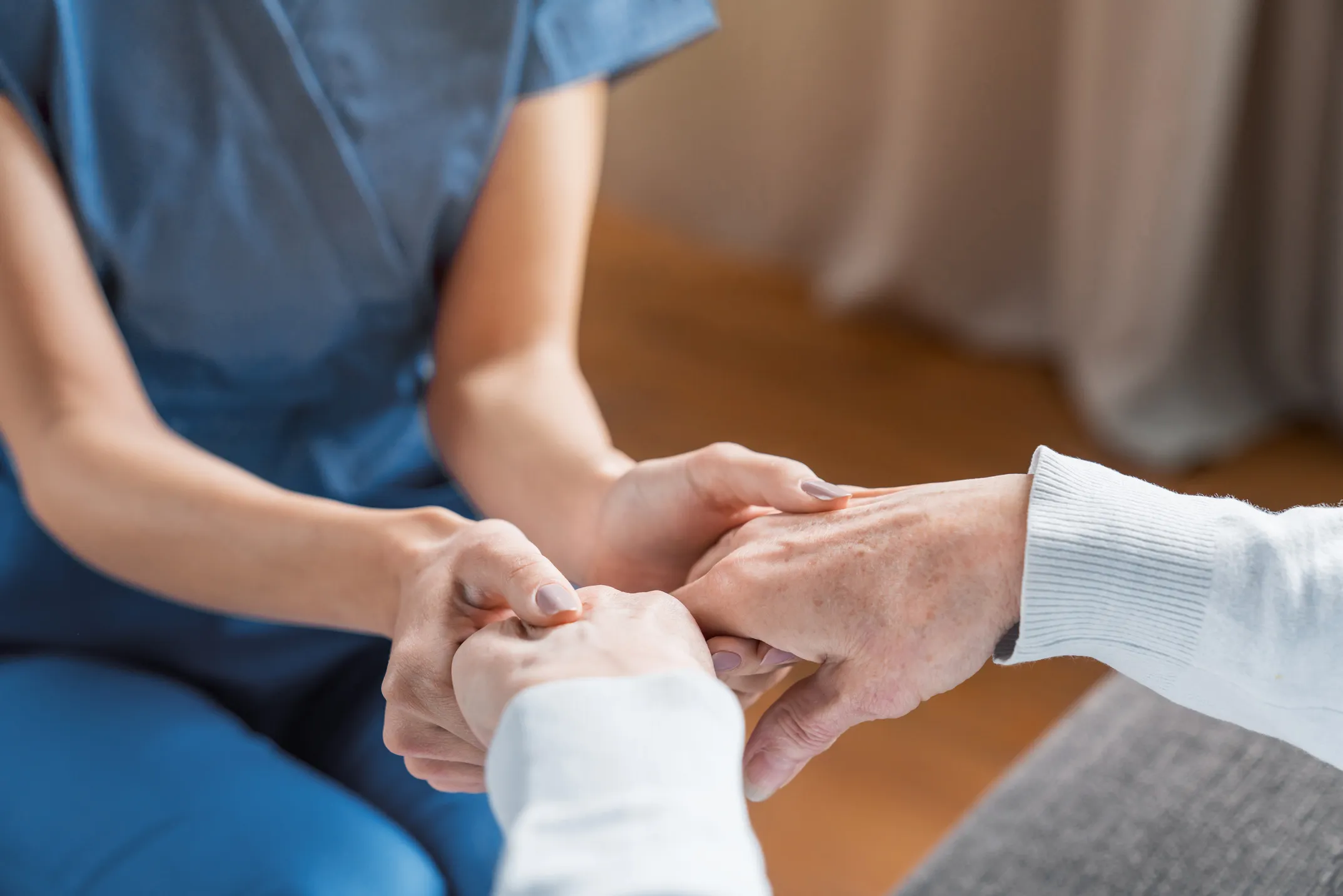 Caregiver gently holding an older adult's hands