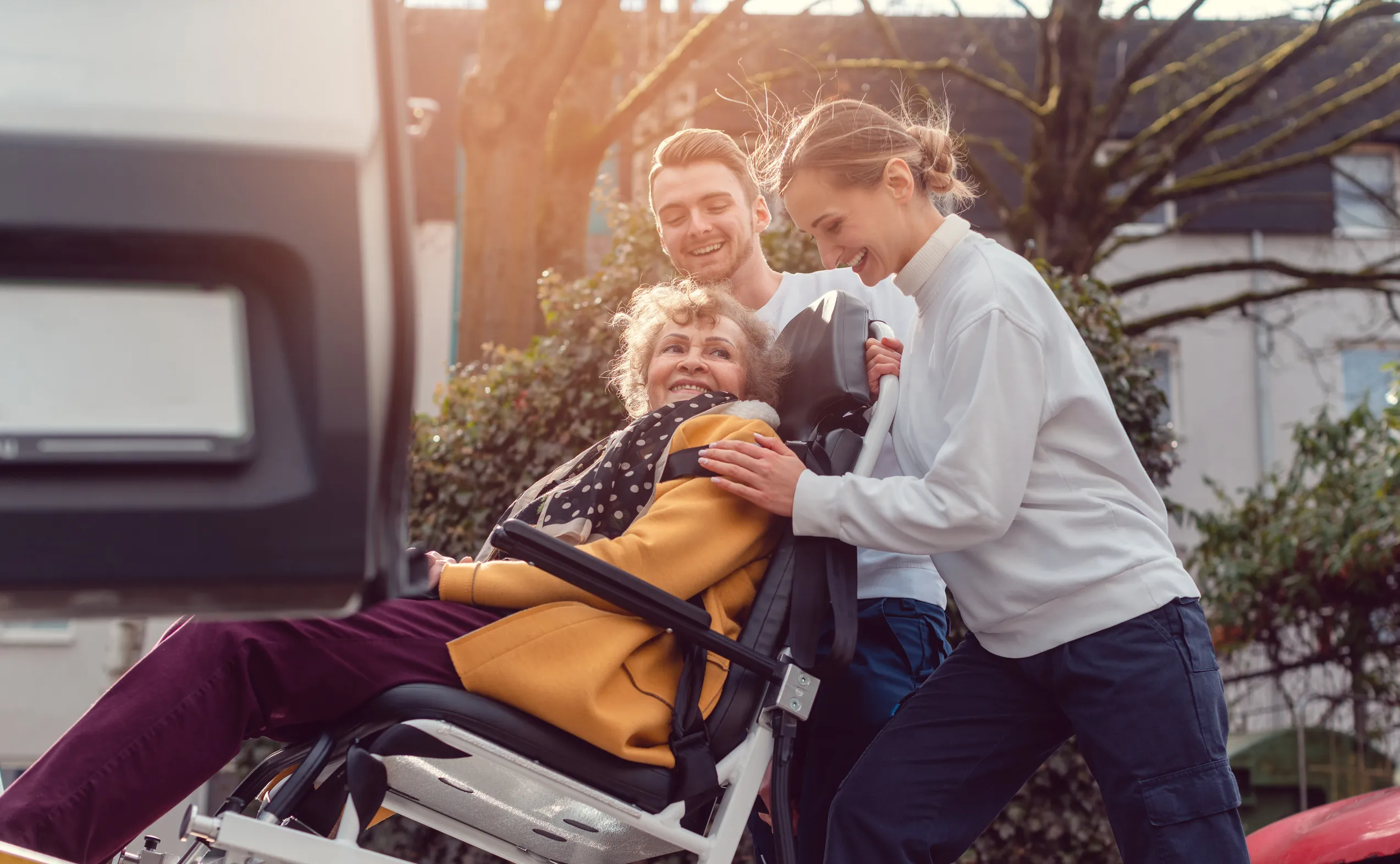 Caregivers helping a smiling older woman in a wheelchair