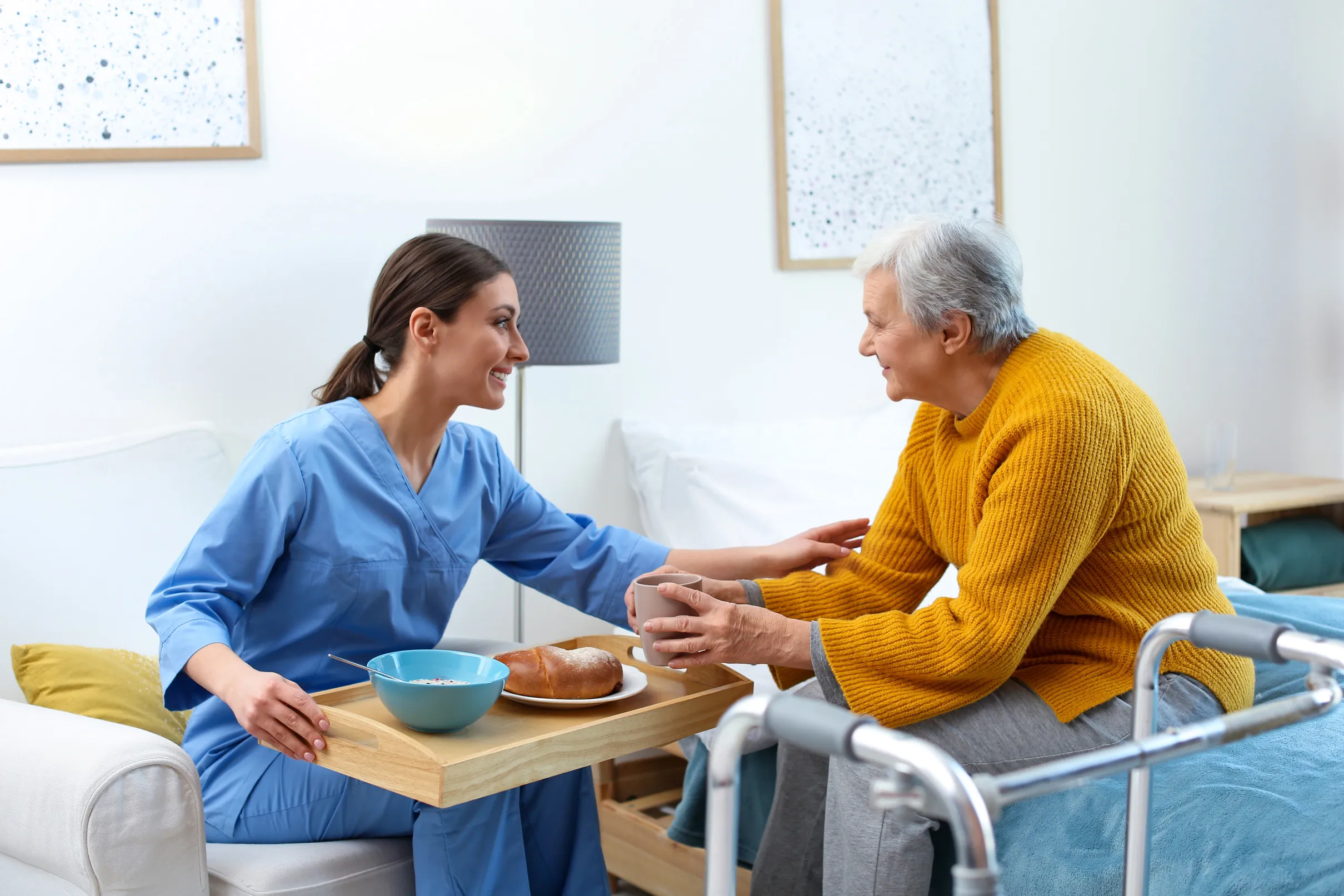 Caregiver serving a meal to a smiling older woman