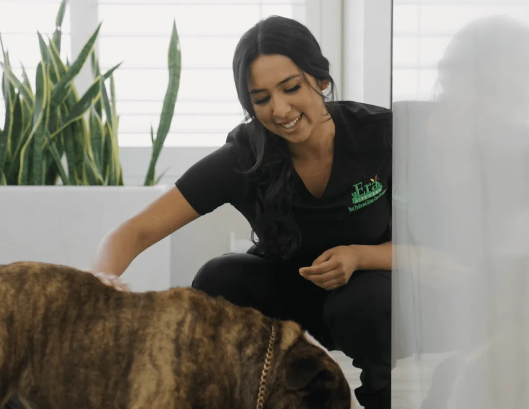 Smiling Era Life Care caregiver greeting a client's dog at home