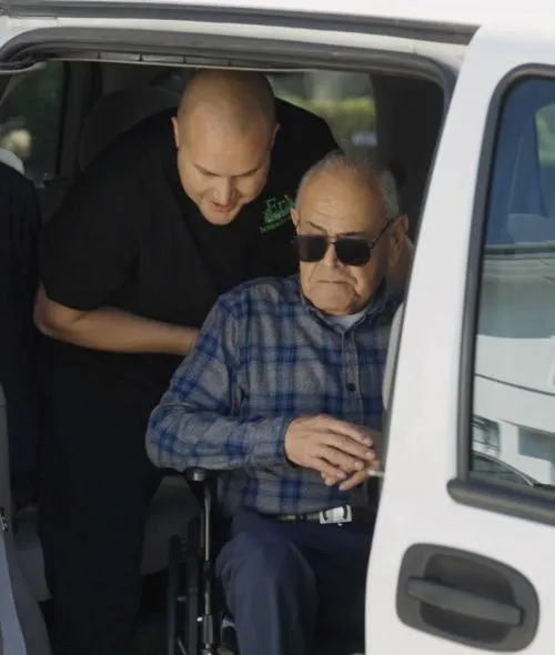 Caregiver helping patient out of the van
