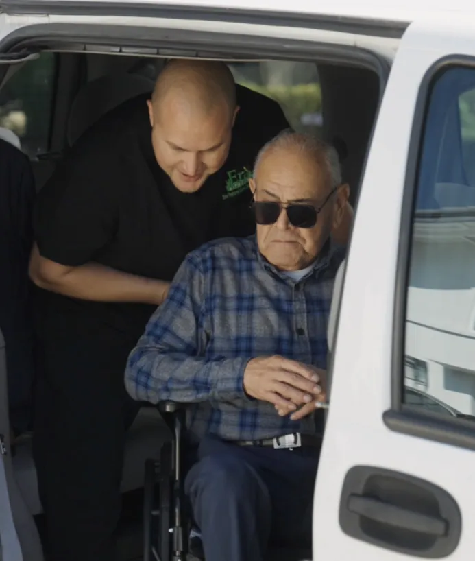 Caregiver helping a client in a wheelchair out of a van